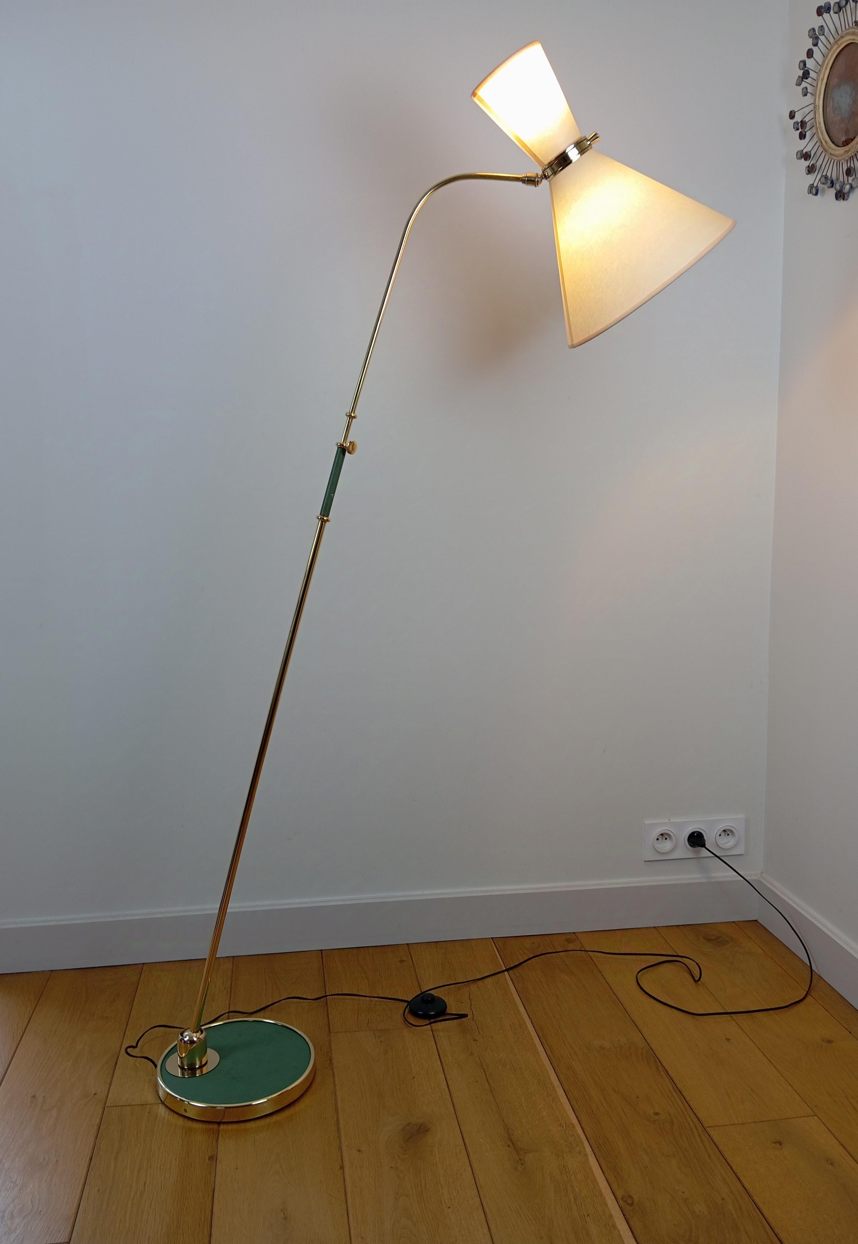  Brass floor lamp,
consisting of a circular cast-iron base, sheathed in green moleskin and set with a brass ring.
Brass arm adjustable in height, and swiveling by means of a brass ball-and-socket joint on the base.
Lighting by 2 conical shades,