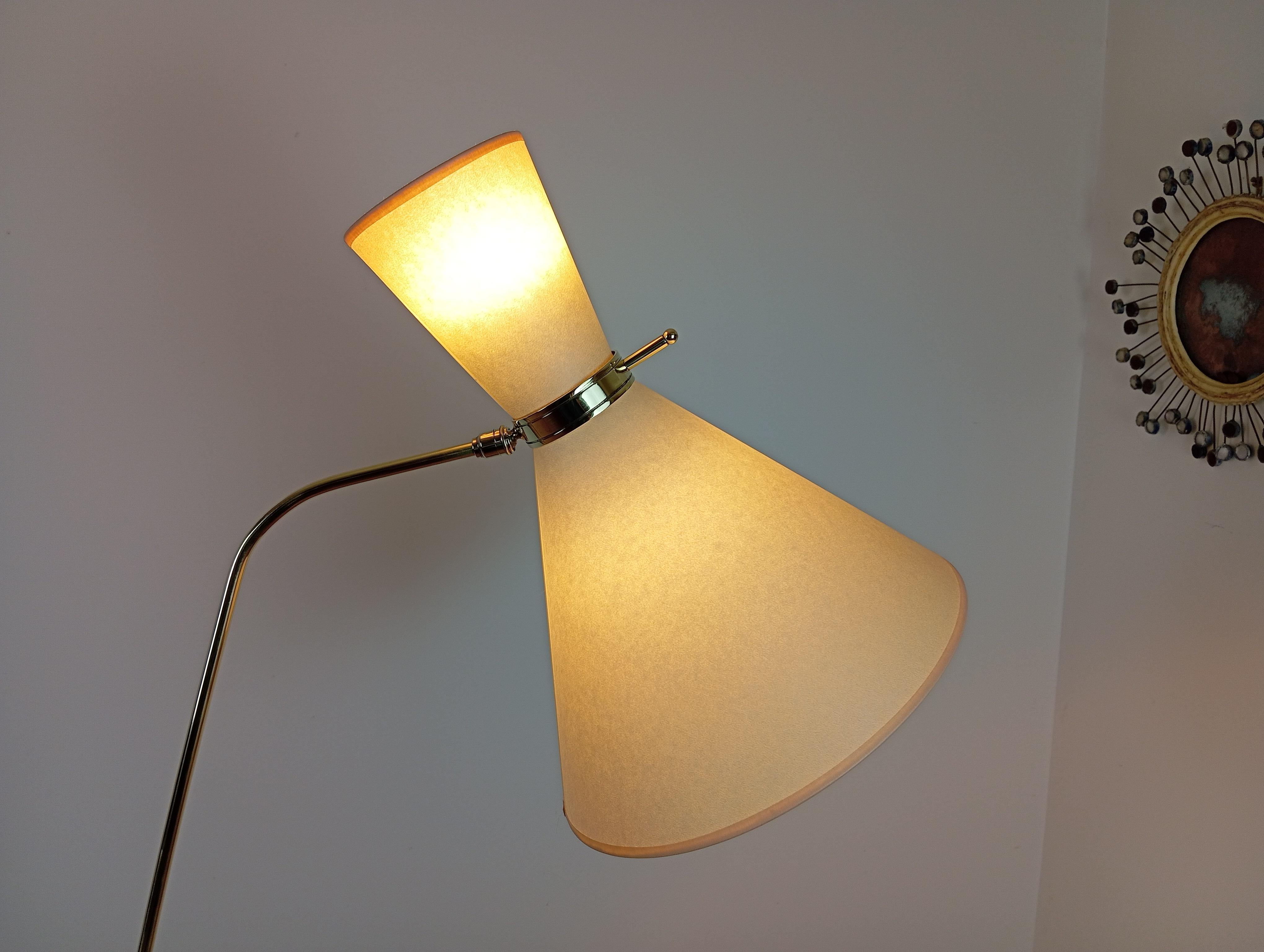  Brass floor lamp,
consisting of a circular cast-iron base, sheathed in red moleskin and set with a brass ring.
Brass arm adjustable in height, and swiveling by means of a brass ball-and-socket joint on the base.
Lighting by 2 conical shades,