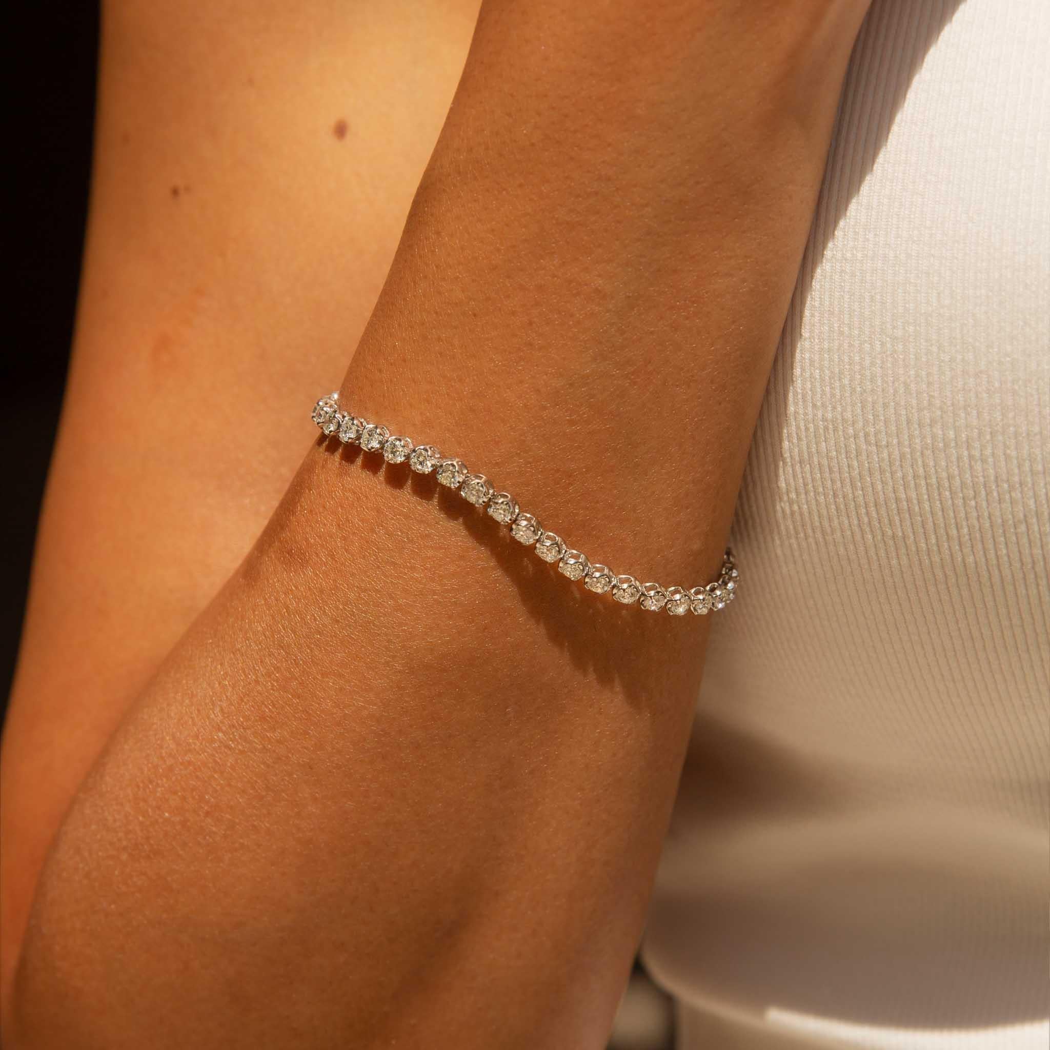 Our exquisite Penelope Diamond Tennis Bracelet is a shimmering masterpiece of contemporary elegance, a twinkling tapestry of precious stones. Her delicate chain of meticulously cut diamonds, each one a brilliant gem, adorn the wrist with a dazzling