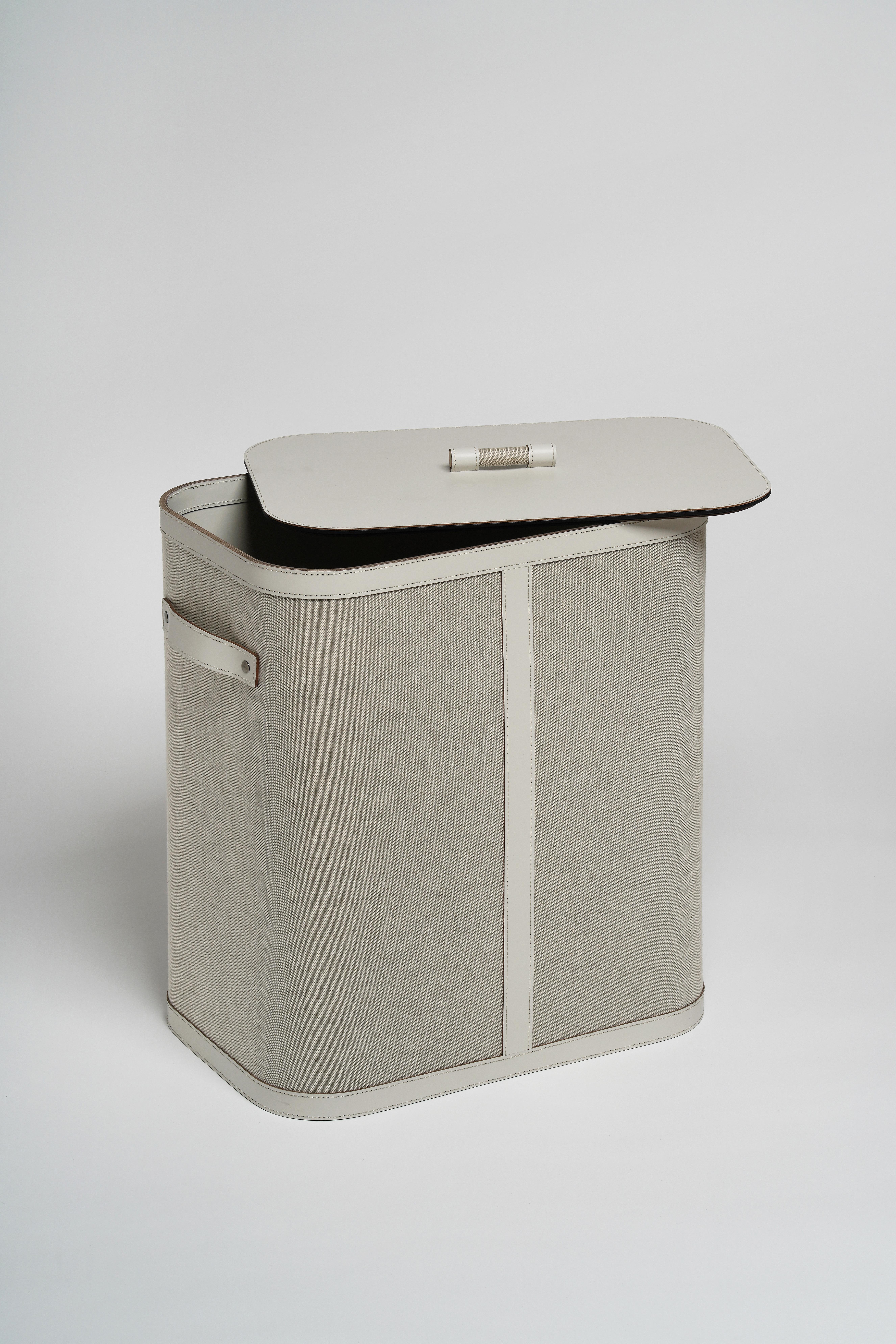 Handcrafted of upcycled leather and textiles, this stunning laundry basket has a bold rectangular silhouette with curved edges and slender sides. The black stitching around the white leather tip on top, bottom, and handles stand out against the soft