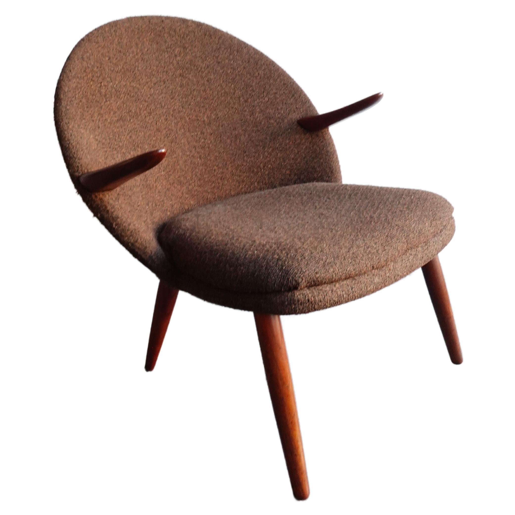 A lovely example of Kurt Olsen’s celebrated ‘Penguin’ chair in original boiled wool upholstery and sculpted teak—excellent vintage condition. Stunning construction featuring floating arms well positioned ergonomically speaking, and a stable splayed