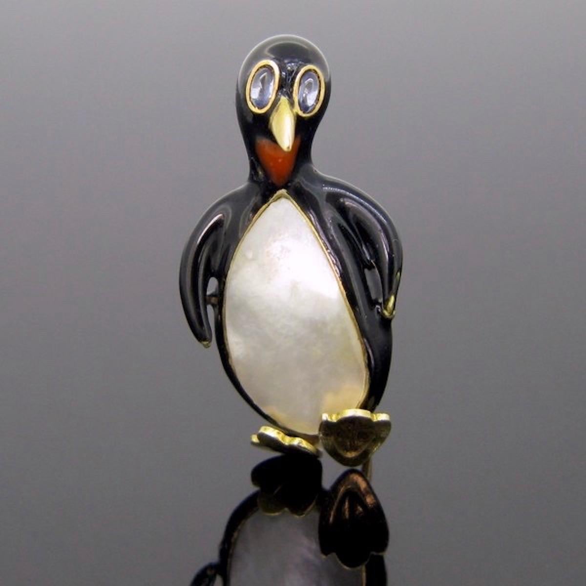 This brooch features a classy penguin made in 18kt gold, mother of pearl and painted in black and red enamel. The eyes are made with 2 cabochon cut sapphires. It is in very good condition. This pin brooch could be wear everyday, it is a funny and