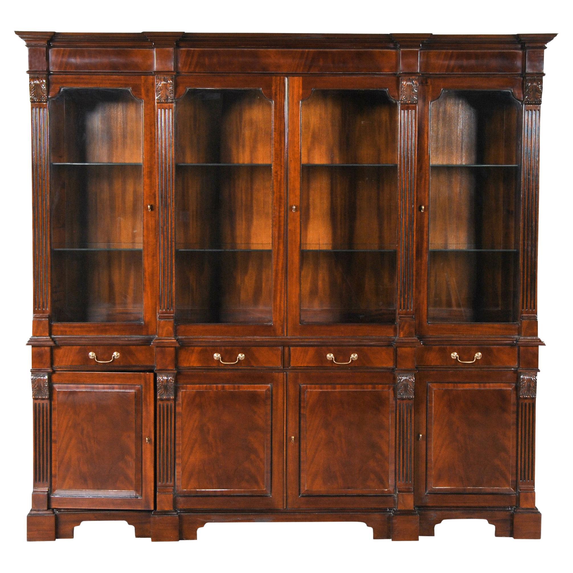 The Penhurst Breakfront comes in two sections. The upper section consisting of a deep molded mahogany veneered cornice following the shape of pillars rising from below, with acanthus carved capitals atop four solid mahogany doors with shaped, open