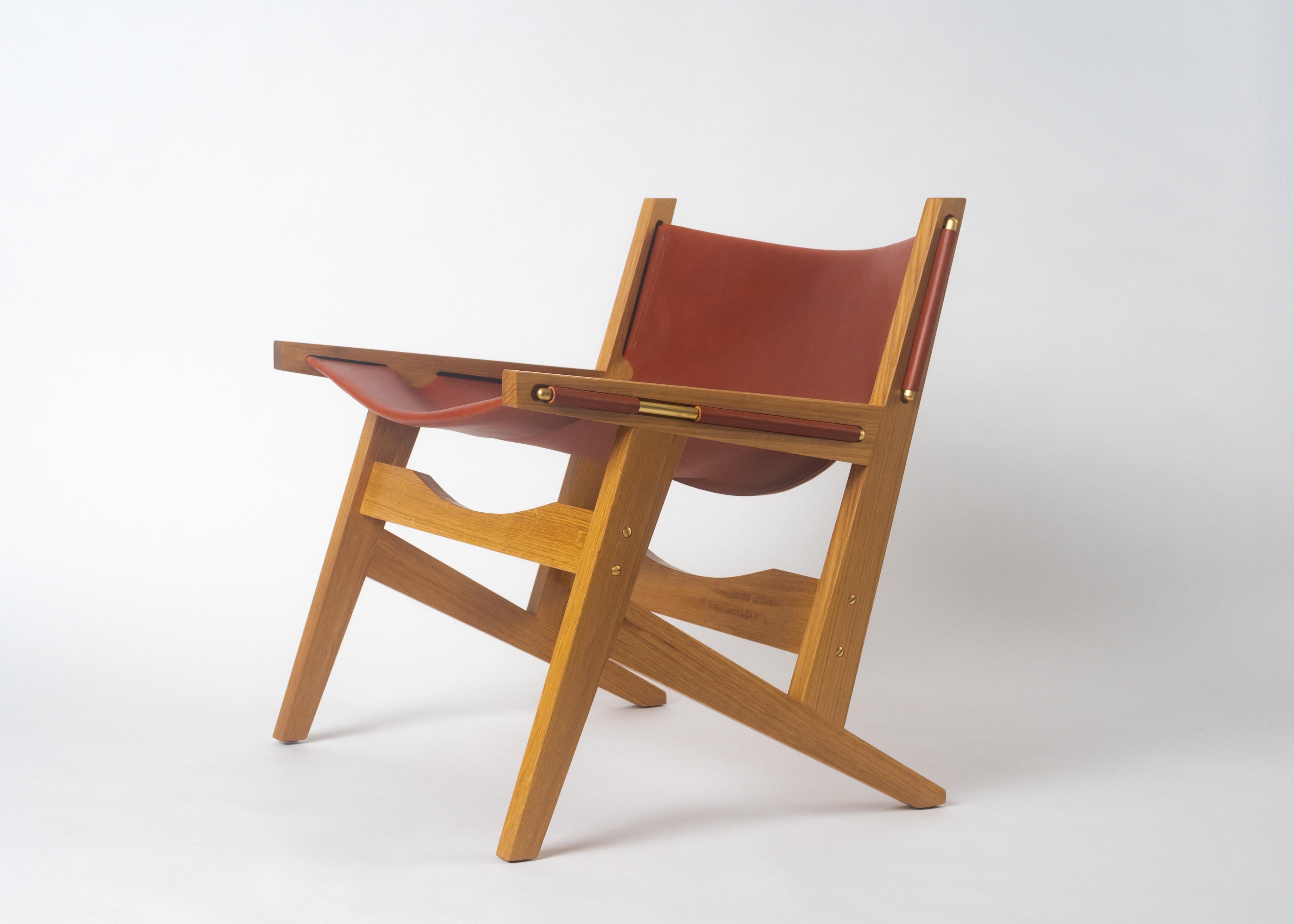 Phloem Studio Peninsula chair is a modern contemporary handcrafted leather sling lounge chair. The hand crafted solid white oak frame holds the heavy weight bridle leather sling in place with solid shaped exposed brass or blackened brass rods.