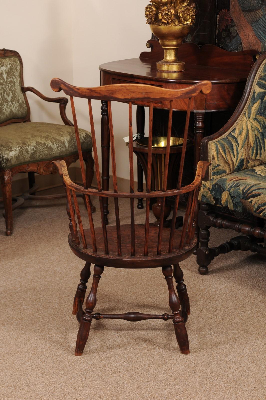 The windsor arm chair with comb-back form, scroll top rail, turned legs and stretcher below. 

  