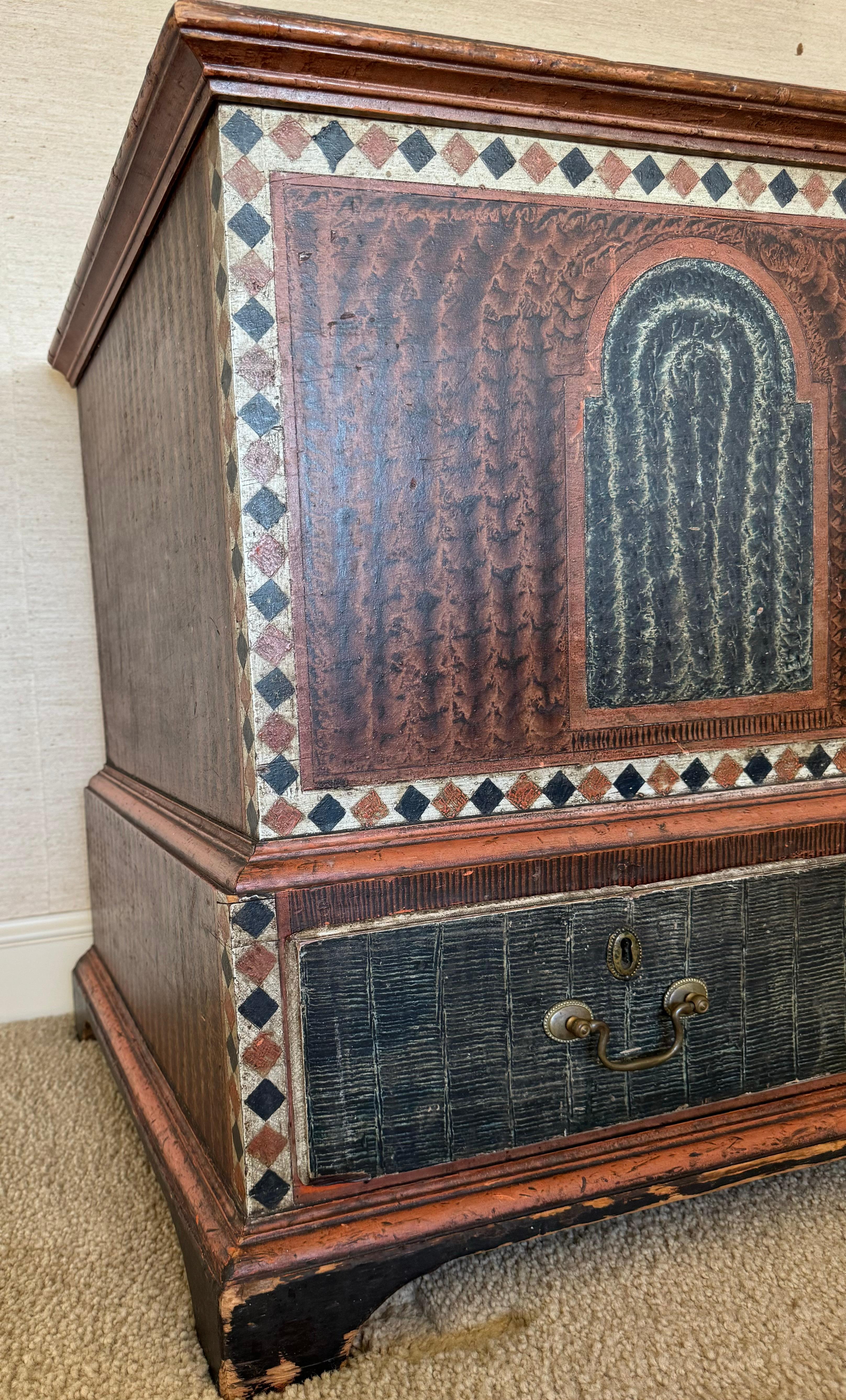 This dower chest  is made of pine and poplar with the original painted finish. The pine case is sponge decorated in salmon with three blue sponged tombstone panels across the front above the sponge drawers outlined in a salmon and black diamond