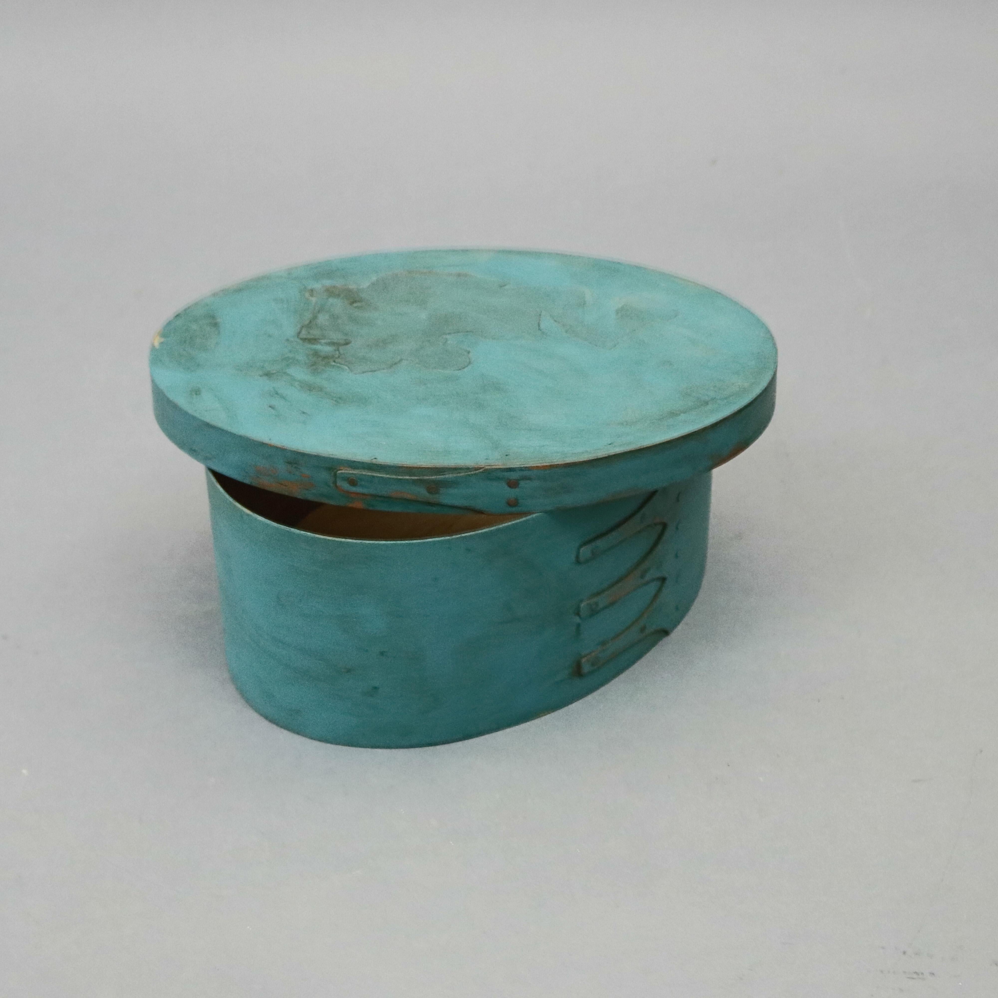 A Pennsylvania Dutch James Lesher School shaker box by offers bentwood maple and birch pegged construction in oval form with four Gothic-shaped finger joints (swallowtails) finished in copper tacks, robins egg blue, 20th century.

Measures: 4.5