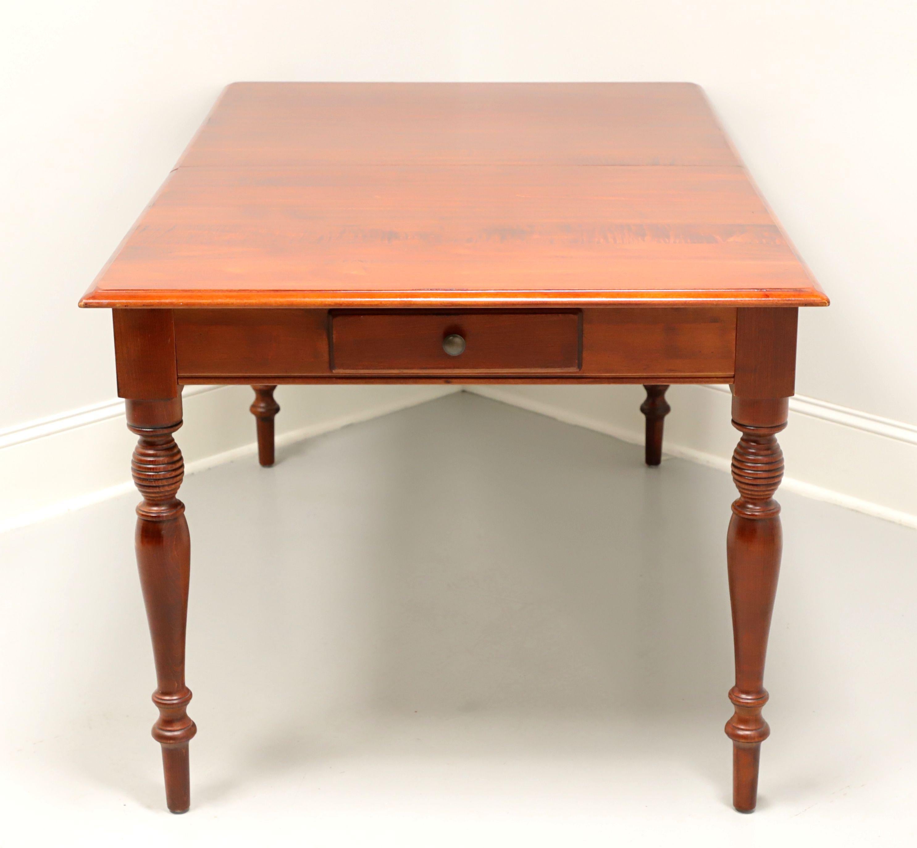 A Farmhouse style dining table by Pennsylvania House. Solid cherry with rectangular top, apron with one dovetail drawer at each narrow end and four turned legs. Includes two extension leaves for placement on metal expansion sliders. Made in the USA,