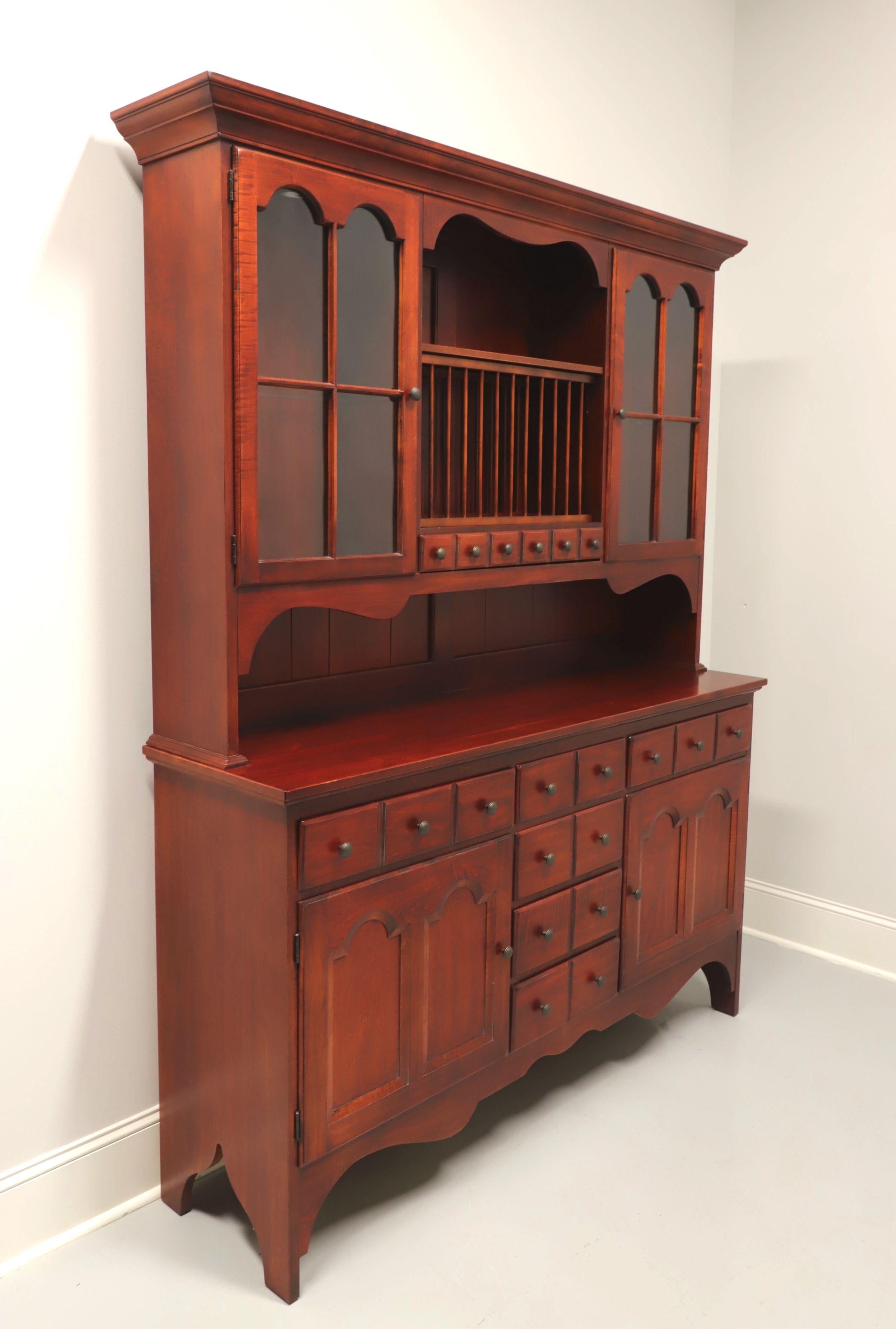 A Farmhouse style hutch by Pennsylvania House. Solid cherry with brass hardware, crown molding to top, carved apron and solid cut board feet. Upper cabinet has a plank back, an upper center shelf with removable plate rack beneath it, which is over
