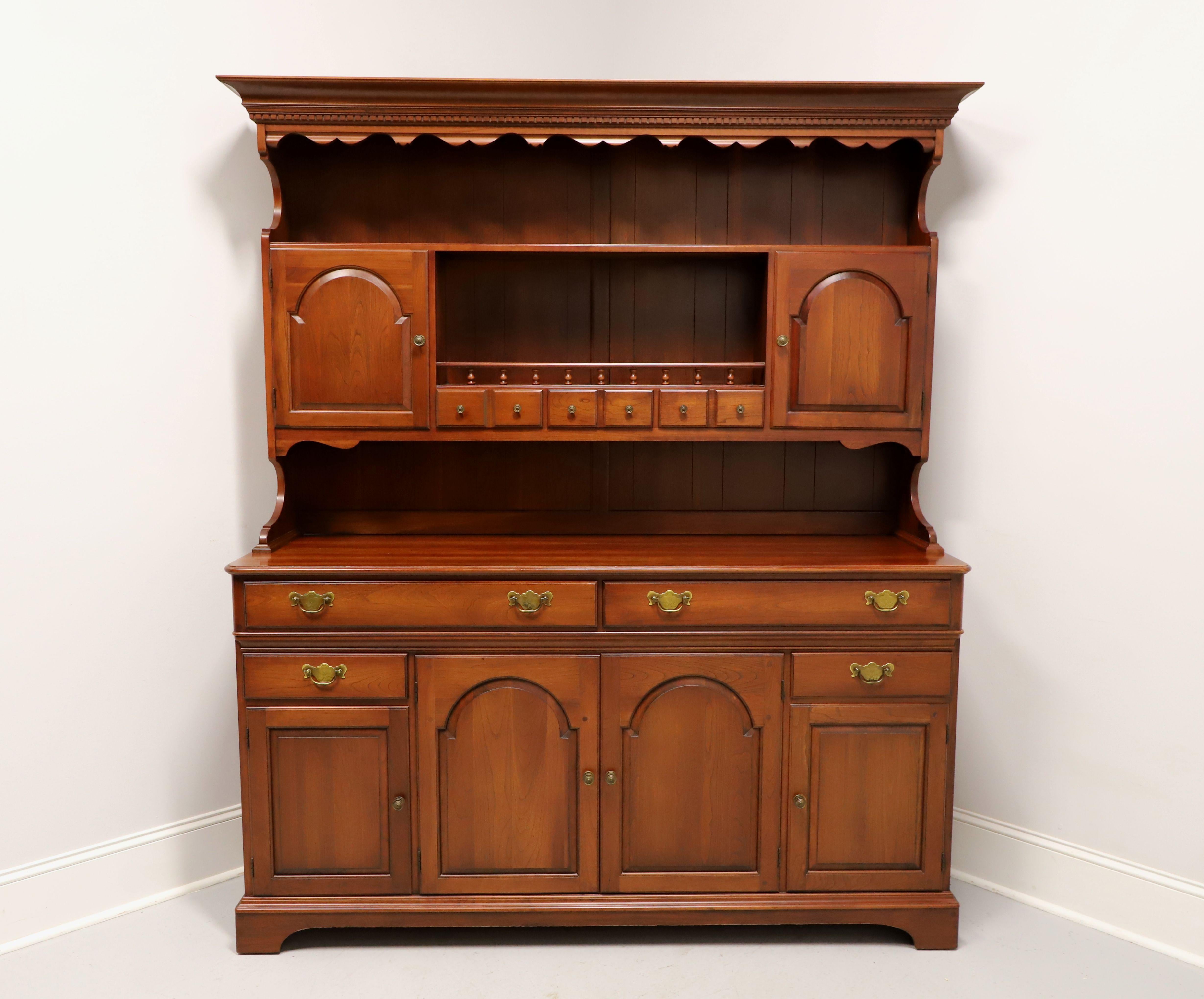 A Colonial style farmhouse hutch by Pennsylvania House. Solid cherry wood with their Candlelight finish, brass hardware, crown & dentil molding to top, carved sides to top section, bevel edge to top of lower cabinet, and bracket feet. Upper cabinet