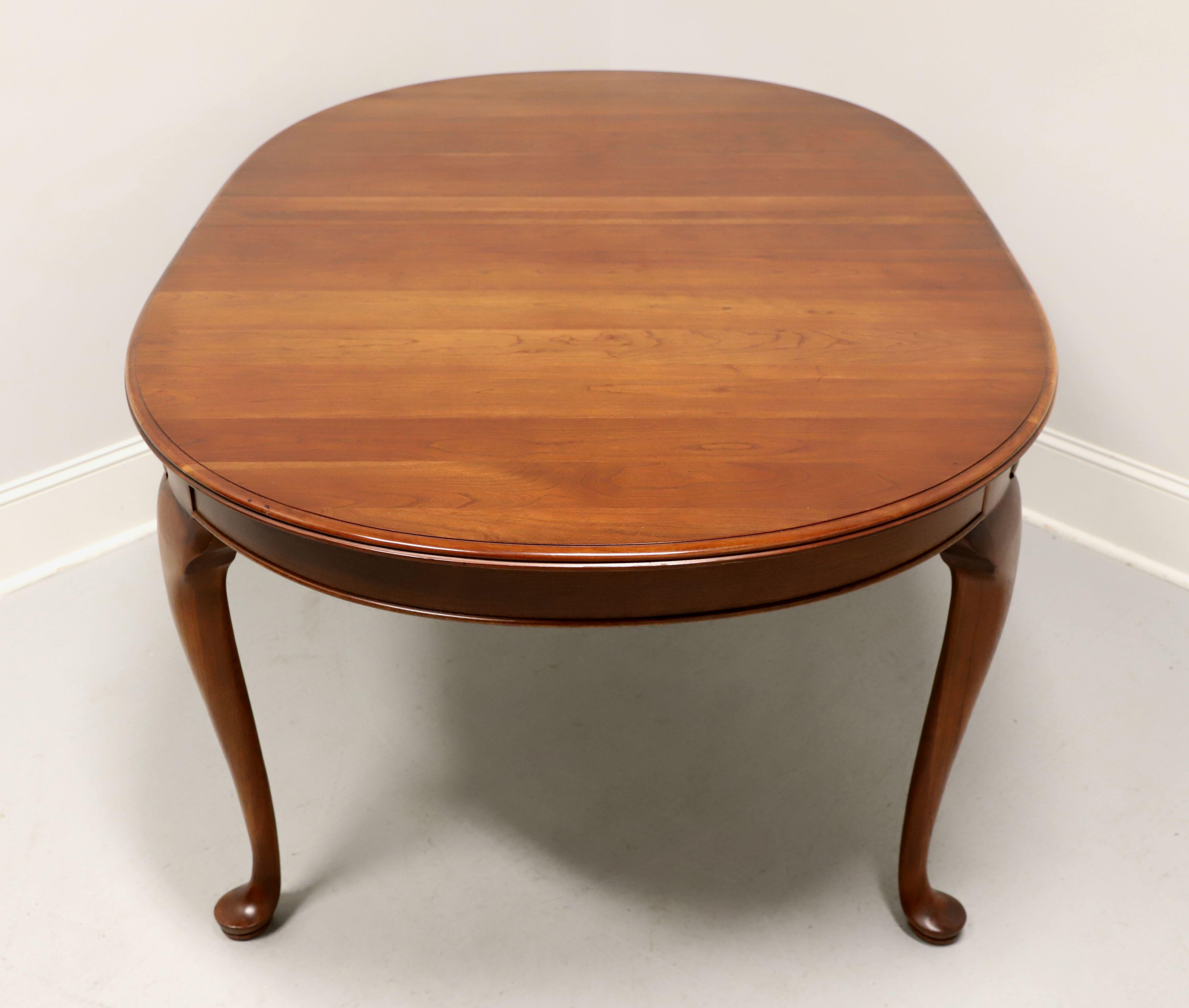 A Queen Anne style oval dining table by Pennsylvania House. Solid cherry wood, bevel edge to the top, solid apron, carved knees, cabriole legs and pad feet. Includes three 10 inch extension leaves for placement on wood expansion sliders. Made in the