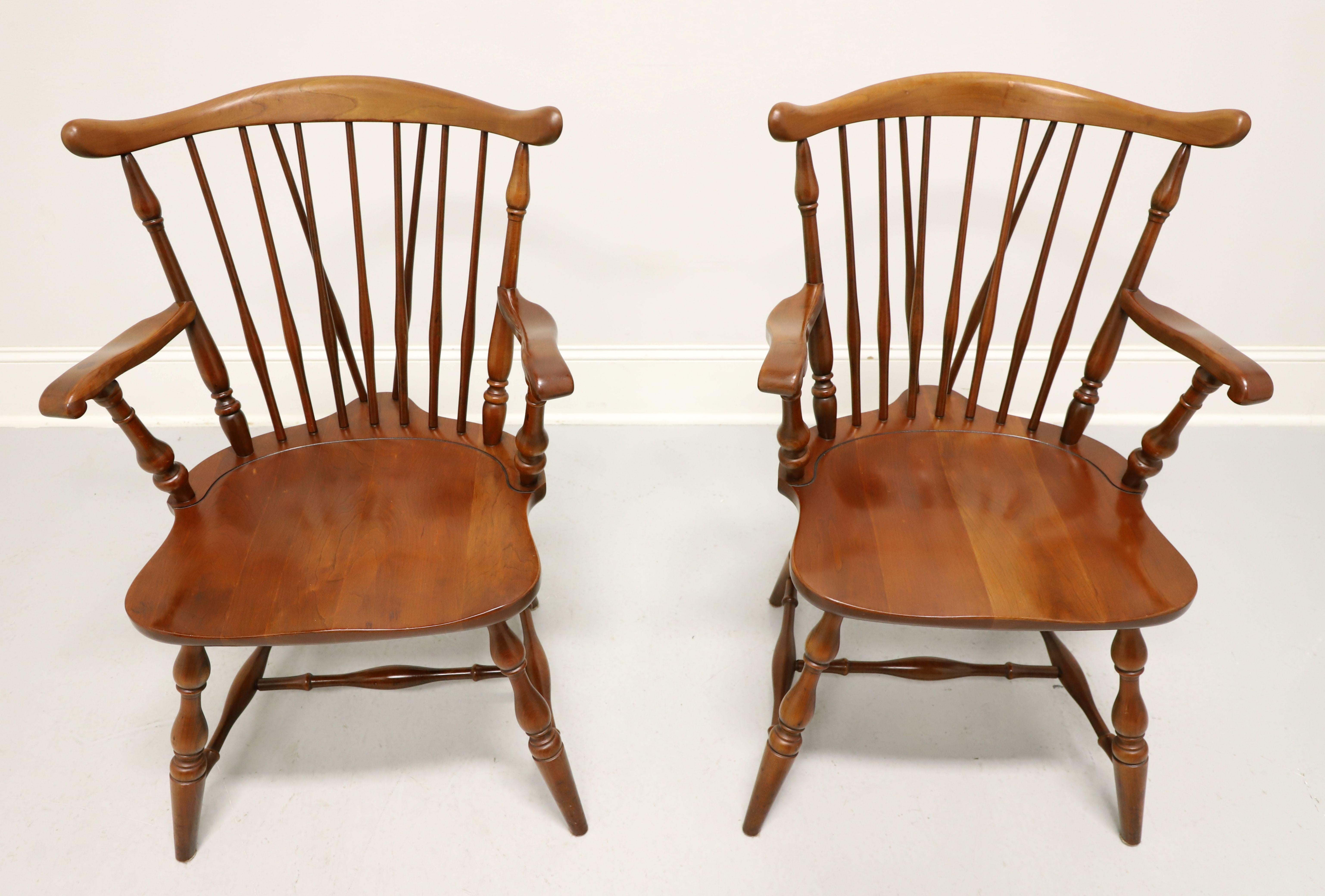 A pair of Windsor style dining armchairs by Pennsylvania House. Solid cherry wood, fiddleback with turned side spindles, gently curved arms with turned spindle supports, saddle shape seat, tail-supports with spindles, turned legs and stretchers.