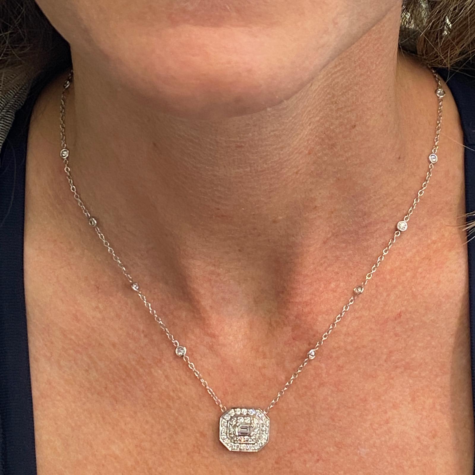 Emerald cut diamond pendant necklace by designer Penny Preville fashioned in 18 karat white gold. The pendant features an emerald cut diamond weighing approximately .26 carats surrounded by round brilliant cut diamonds weighing 1.25 carat total