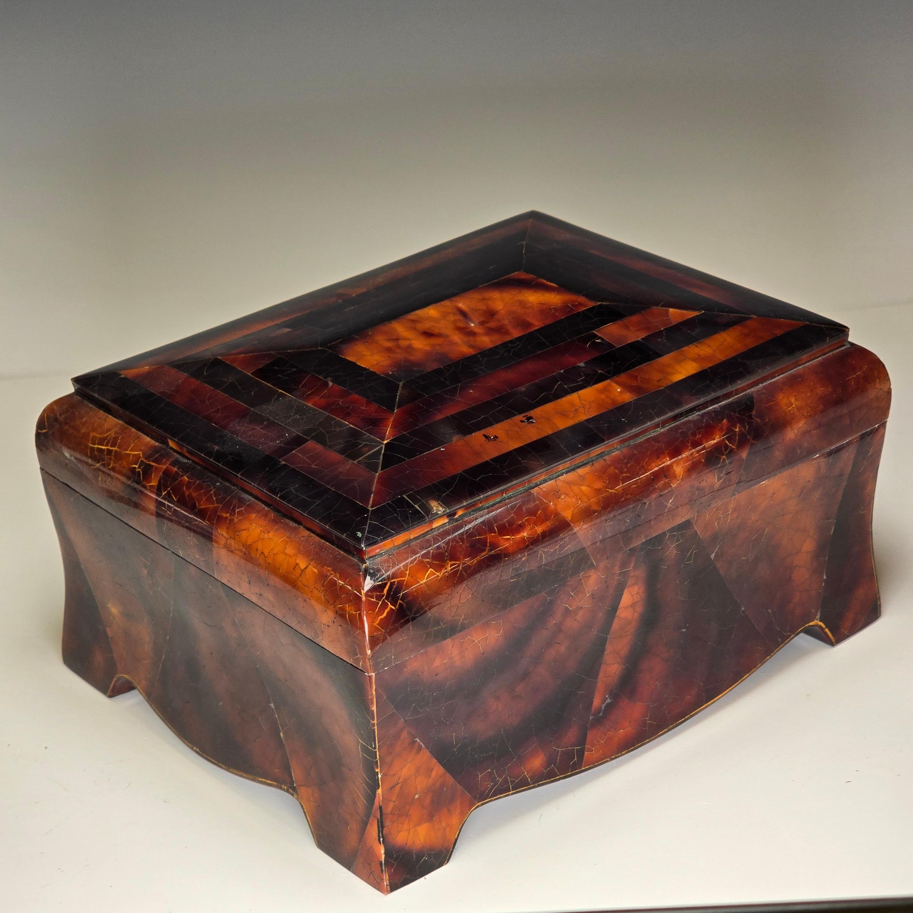 Impresionante caja de madera con forma de cofre, recubierta de incrustaciones teseladas de concha y cuerno, con aspecto de caparazón de tortuga.  Muy similar a las cajas de Karl Springer de la misma época.   