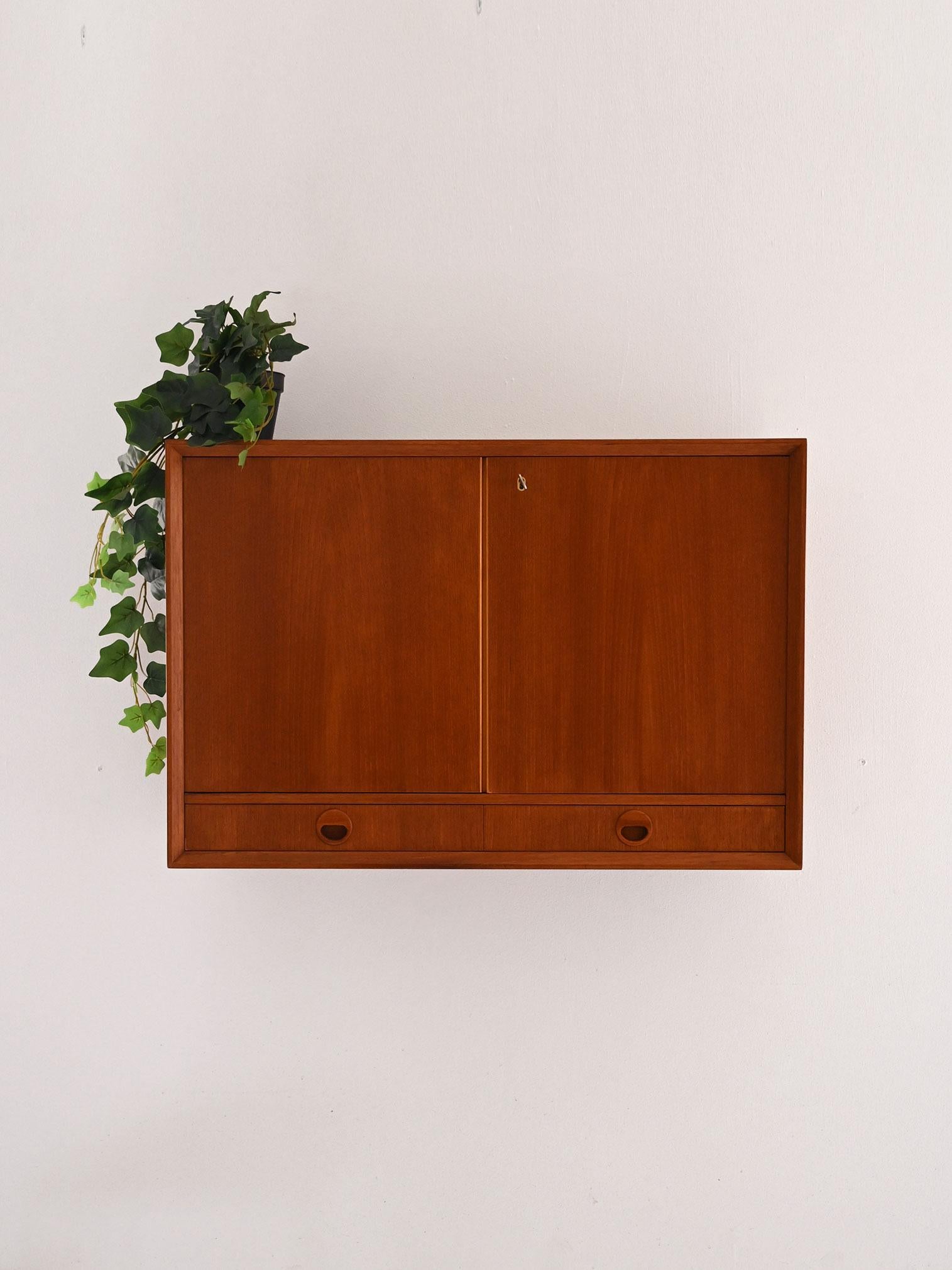 Mueble alto escandinavo con dos puertas, estante interior y dos cajones con tiradores redondos tallados.

Original armario de pared escandinavo de teca de los años 60. Equipado con dos puertas batientes con cerradura de funcionamiento y llave
