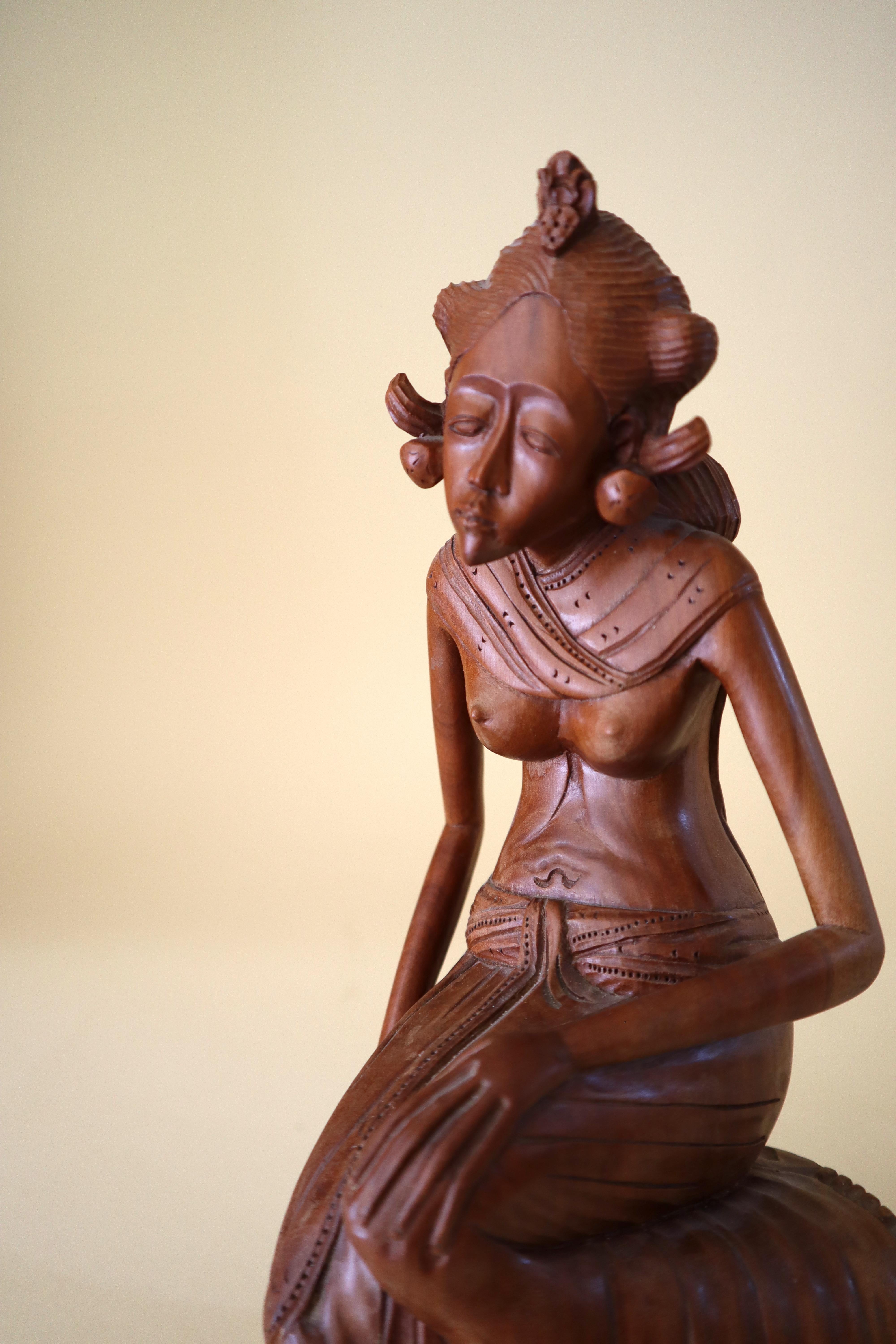 Something like the famous Little Mermaid in Copenhagen, this elegantly dressed Balinese Lady gazes pensively out into the distance, seeming to have many thoughts on her mind. Her long sarong or wrap-around skirt falls over and down the side of the