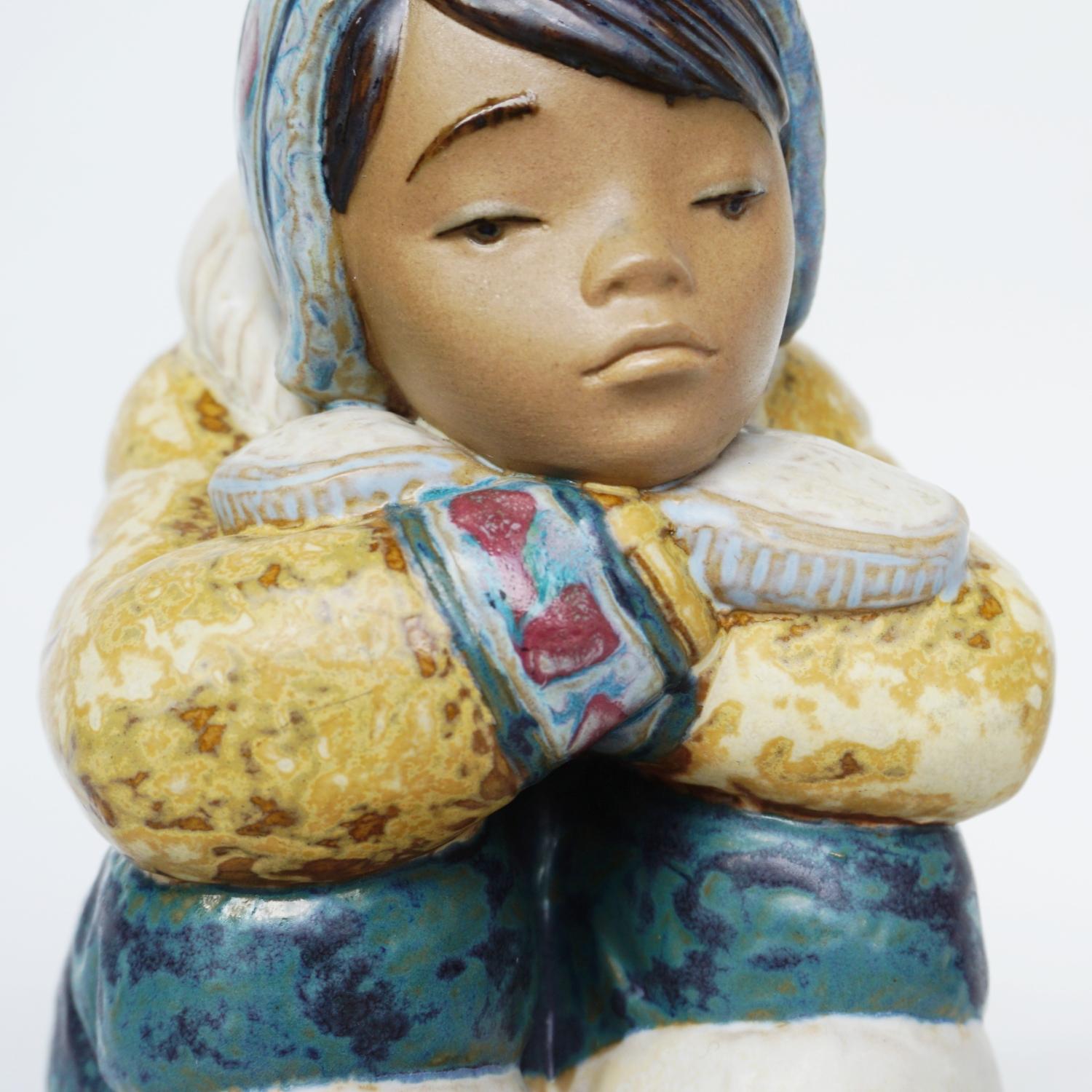 'Pensive Inuit Boy' pottery figure sculpted by Francisco Catalá for Lladró. First issued in 1985. Depicting a young Inuit boy sitting with his face resting on crossed arms. Excellent fine hand painted detail. Numbered 2159.

Dimensions: H 16.5cm W