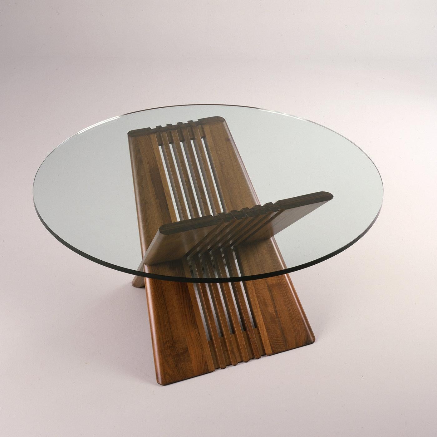 The elegance of this dining table is revealed in its sleek lines and simple proportions. Two stave-shaped cherry sheets intersect to create the base which supports the round top (1.9 cm thick). The ultra-clear tempered glass top with a glossy edge