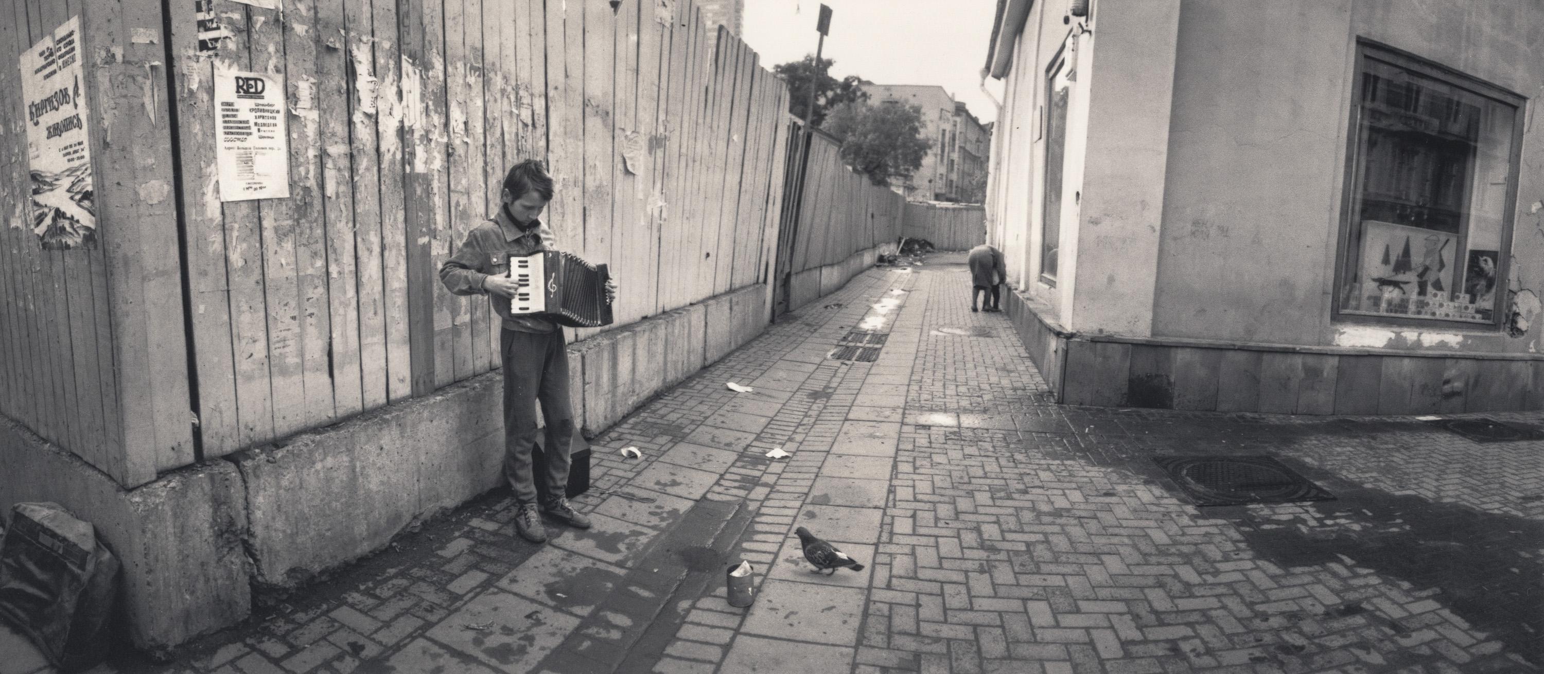 Black and White Photograph de Pentti Sammallahti - Moscú, Rusia (Niño tocando el acordeón en la calle)