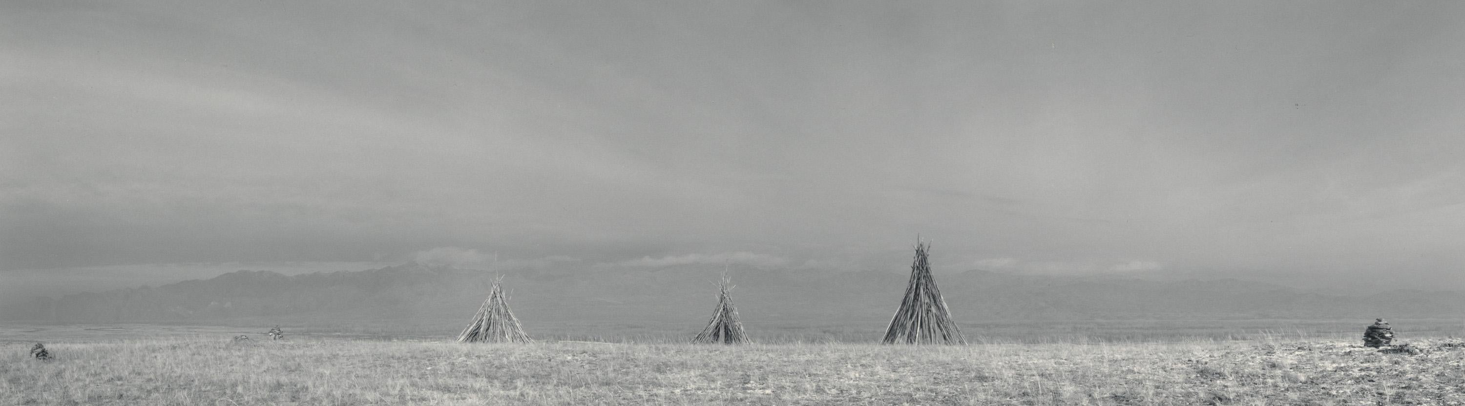 Black and White Photograph Pentti Sammallahti - Sayan, Tuva Siberia (places de cheminée Teepee dans un champ ouvert, ciel d'hiver)