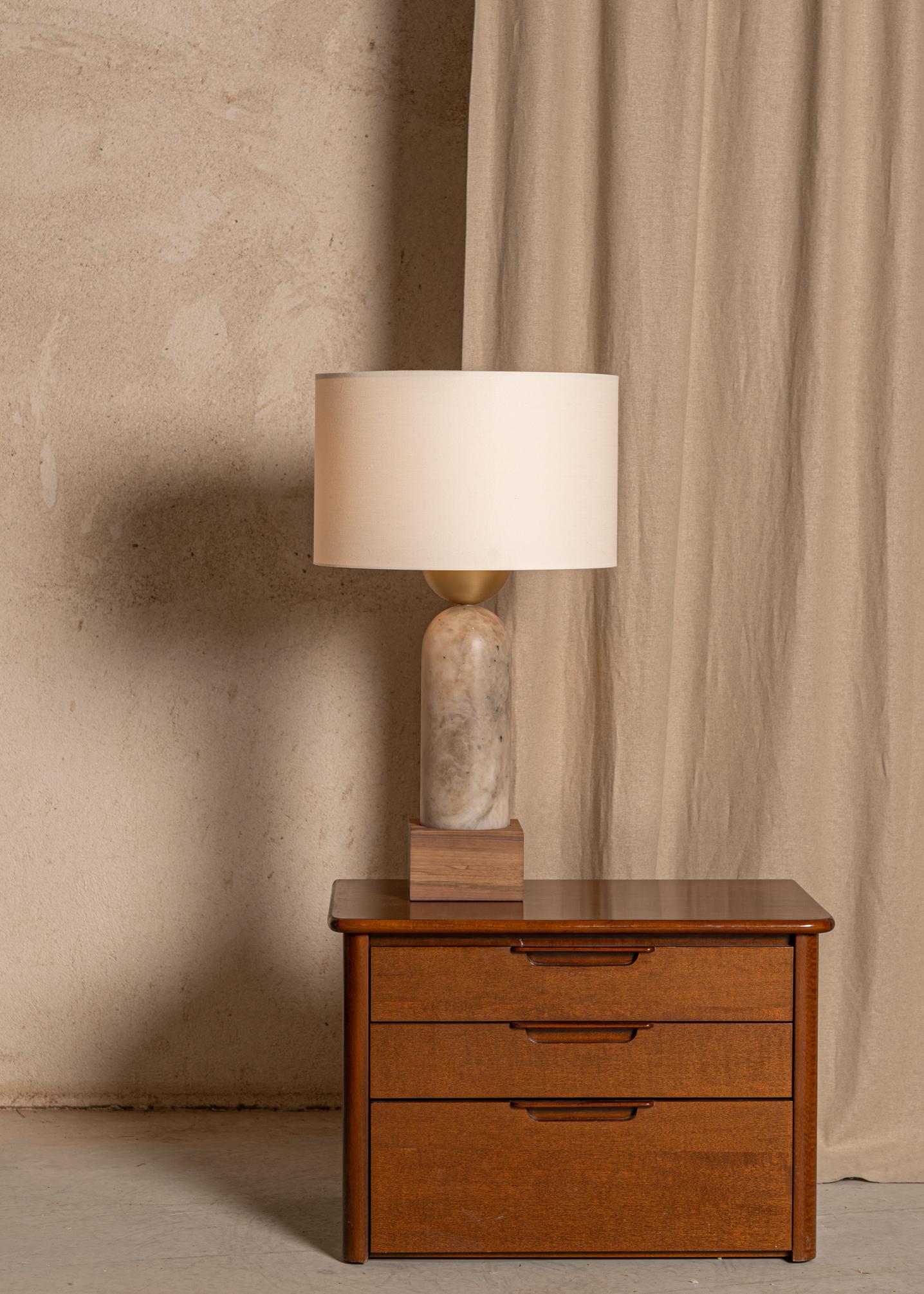 An elevated and elegant association of spherical lines to create a unique shape. Playing with materials and geometries to create contrast, the Peona table lamp merges perfectly in a modern or classical interior. Association of alabaster, marble or