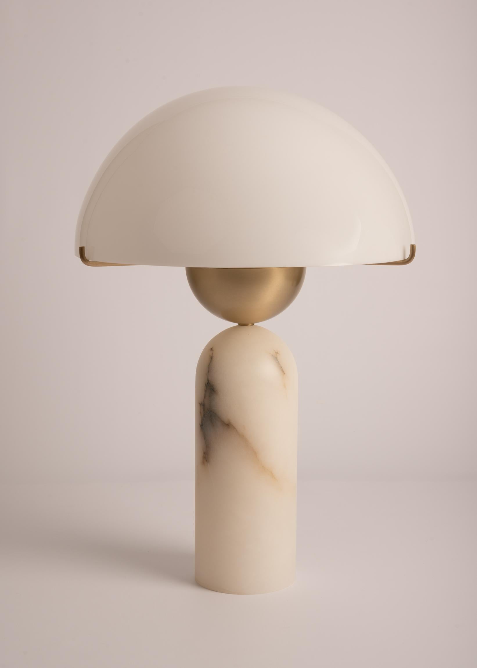 Spherical lines layered elegantly to form a bold, modern shape. The Peono table lamp marries materials and plays with contrasts. Alabaster, marble or wood can be associated to the solid brass halfsphere and its acrylic dome, difusing a soft milky