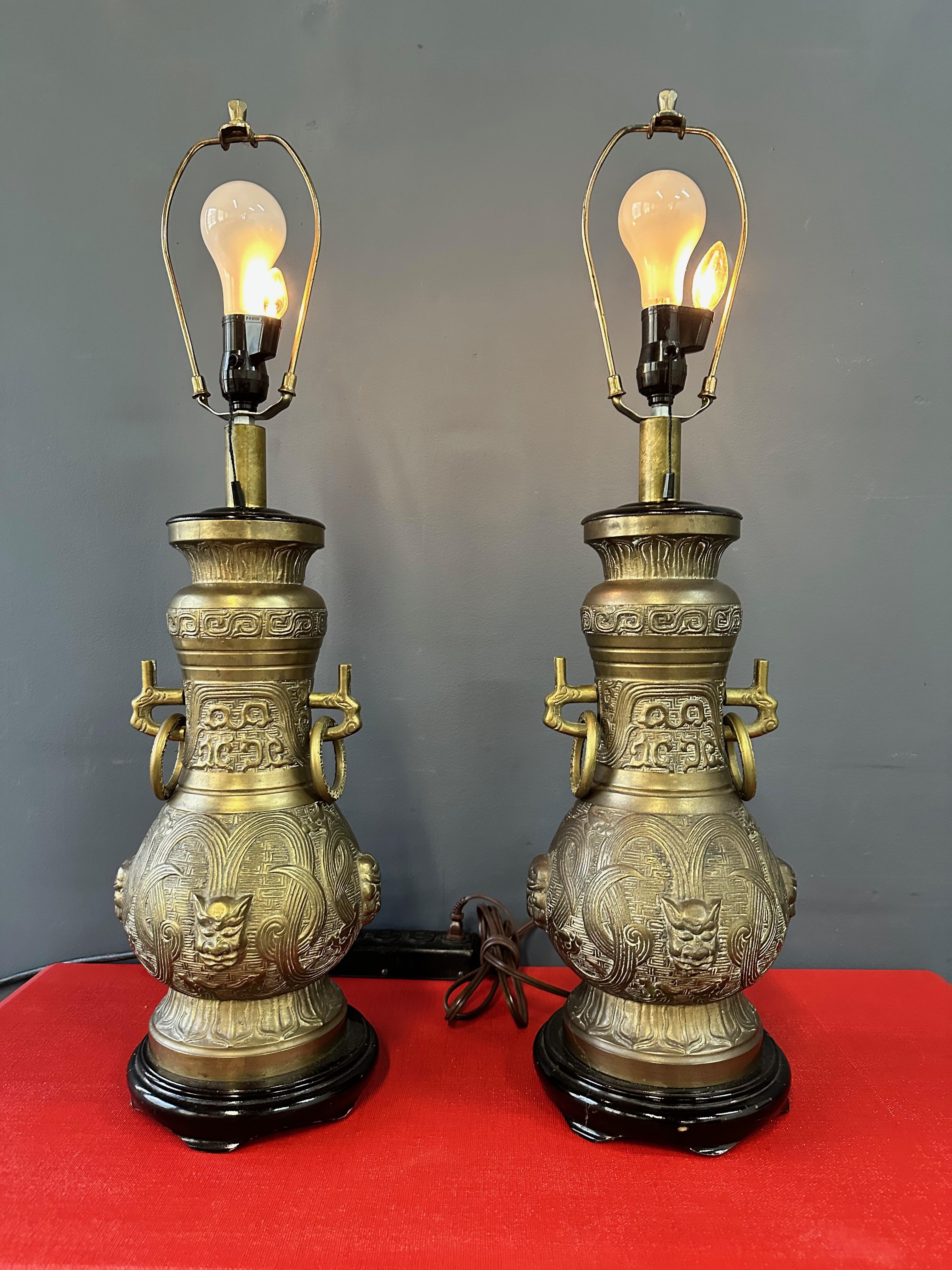 Mid-century bronze table lamps by Pepe Mendoza Featuring ebonized bases, loose rings on the sides with an Oriental jar design. There are three settings for the lighting, the main light only, the small bulb only, or both on at the same time. A brass