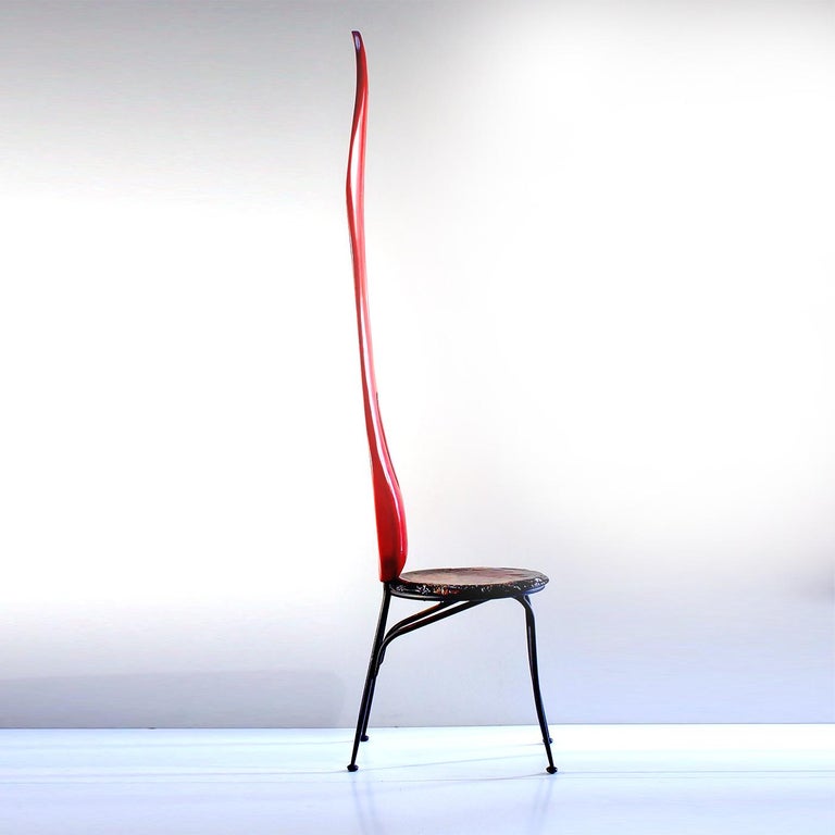 Recalling the shape and color of a chili-pepper, this sculptural chair delivers a strong visual impact with its lively silhouette comprising a lime wood back hand-finished in water-based red paint, all supported by hand forged, black powder-coated