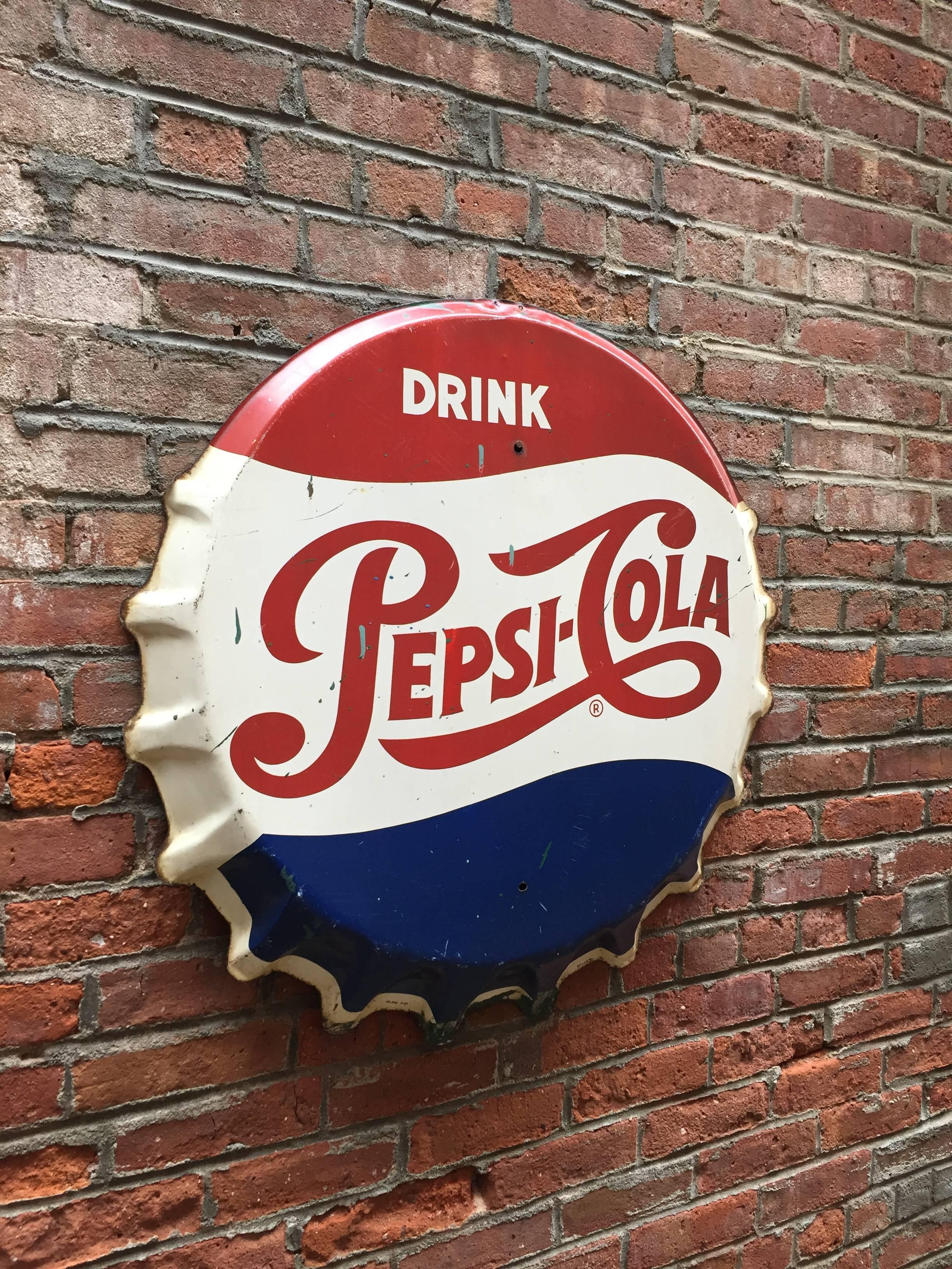 Iconic and rare Pepsi Cola bottle cap sign, circa 1950-1960. Very good original condition with some enamel losses, scratches and light rusting. Some paint drips.

Measures: 29.75
