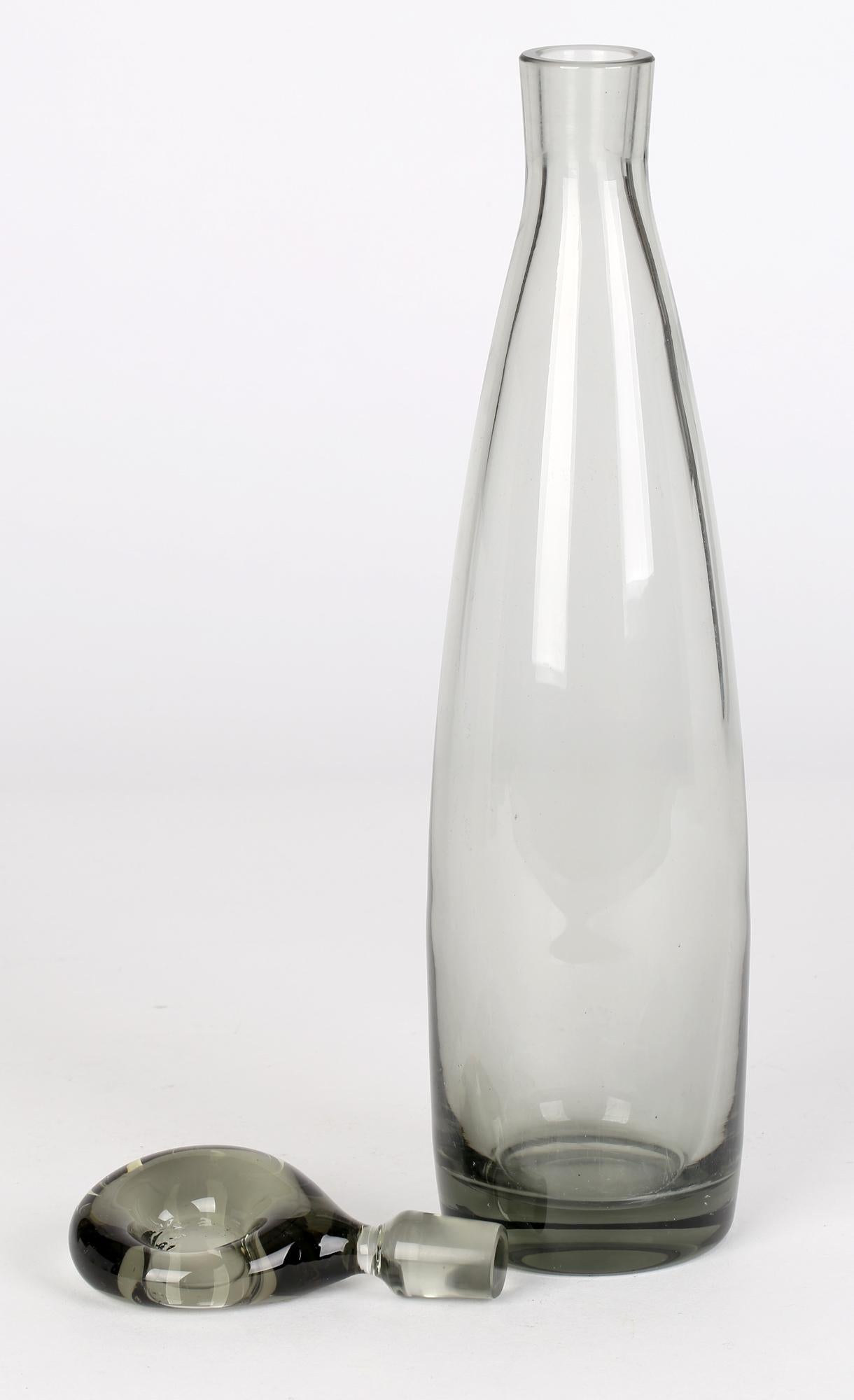 A stylish Mid-Century Danish Holmegaard tinted grey glass Aristokat decanter and stopper designed by Per Lütken (Danish, 1916-1998). This elegant hand-blown glass decanter stands on a wide rounded foot with a recessed polished pontil and is of