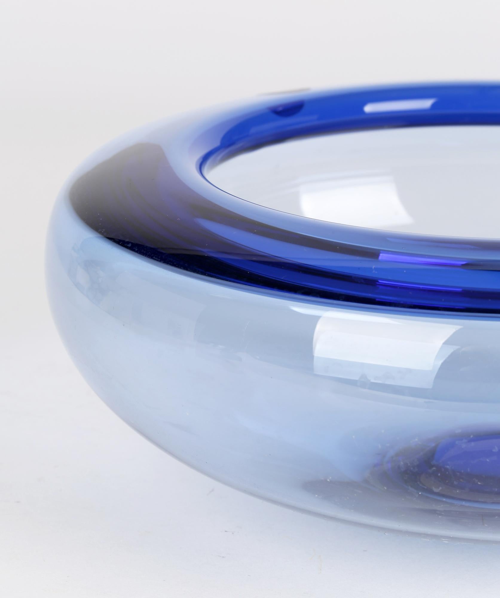 A stylish mid-century Danish Holmegaard small original boxed blue glass bowl designed by Per Lütken (Danish, 1916-1998). This finely made hand blown glass bowl is of wide shallow rounded form with a folded in thicker and consequently darker blue
