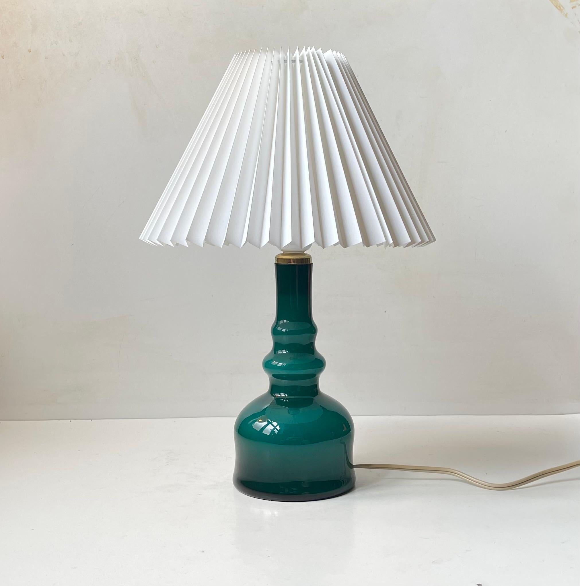 A teal green cased glass table lamp designed by Per-Olaf Ström in the 1960s and made at Alsterfors Glasbruk in Sweden. Often falsely attributed to Michael Bang for Holmegaard in his Palet series. This table light is fitted with a new fluted