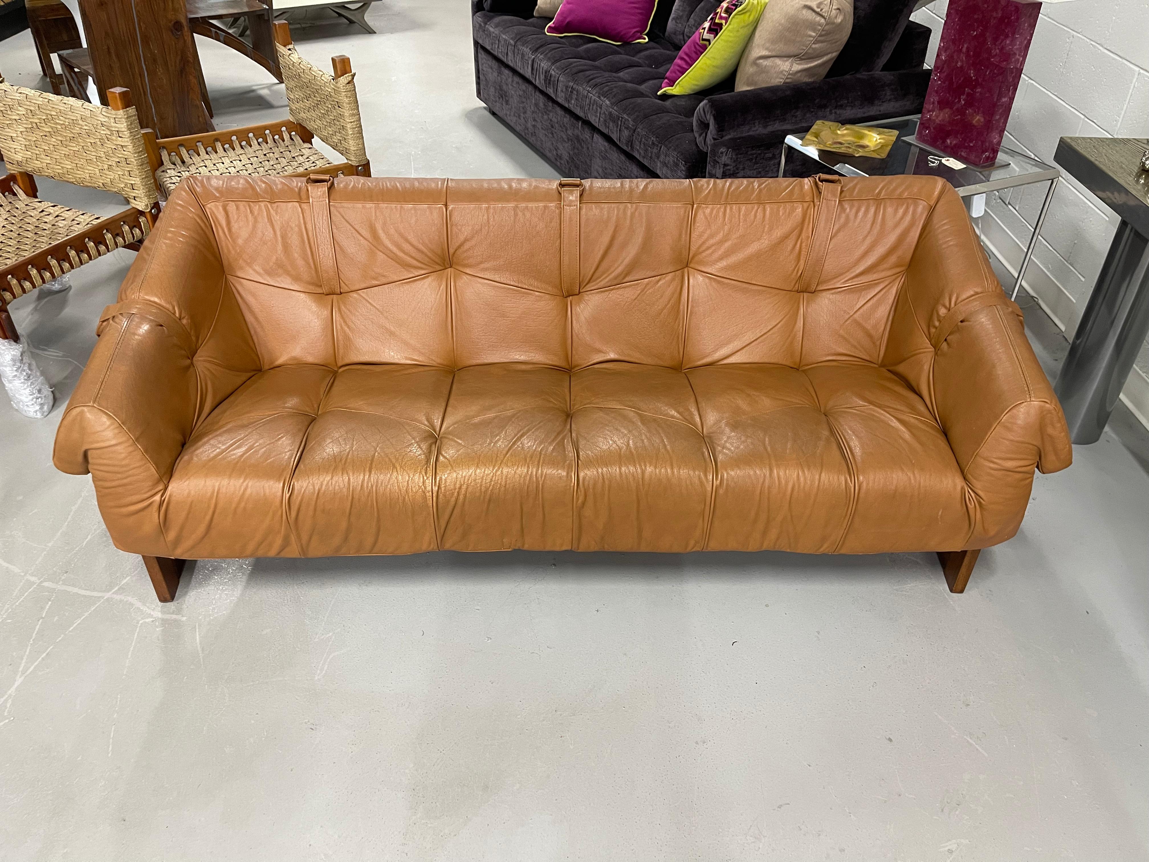 Beautiful vintage 1970's rosewood and cognac colored leather sofa. With a partial original label underneath. Good overall vintage condition to leather with age appropriate wear and marks. The straps underneath have been re-enforced and a couple