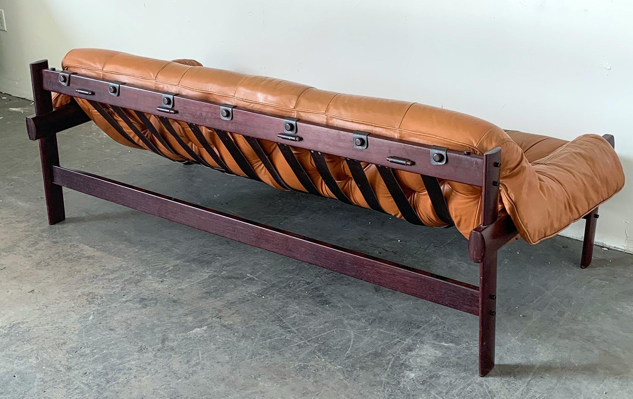 This gorgeous sofa was designed by Percival Lafer in the 1970s and is a sling style sofa. This patinated cognac leather sofa is definitely set off right with its rosewood frame and leather strapping along its back. This is definitely a sofa that