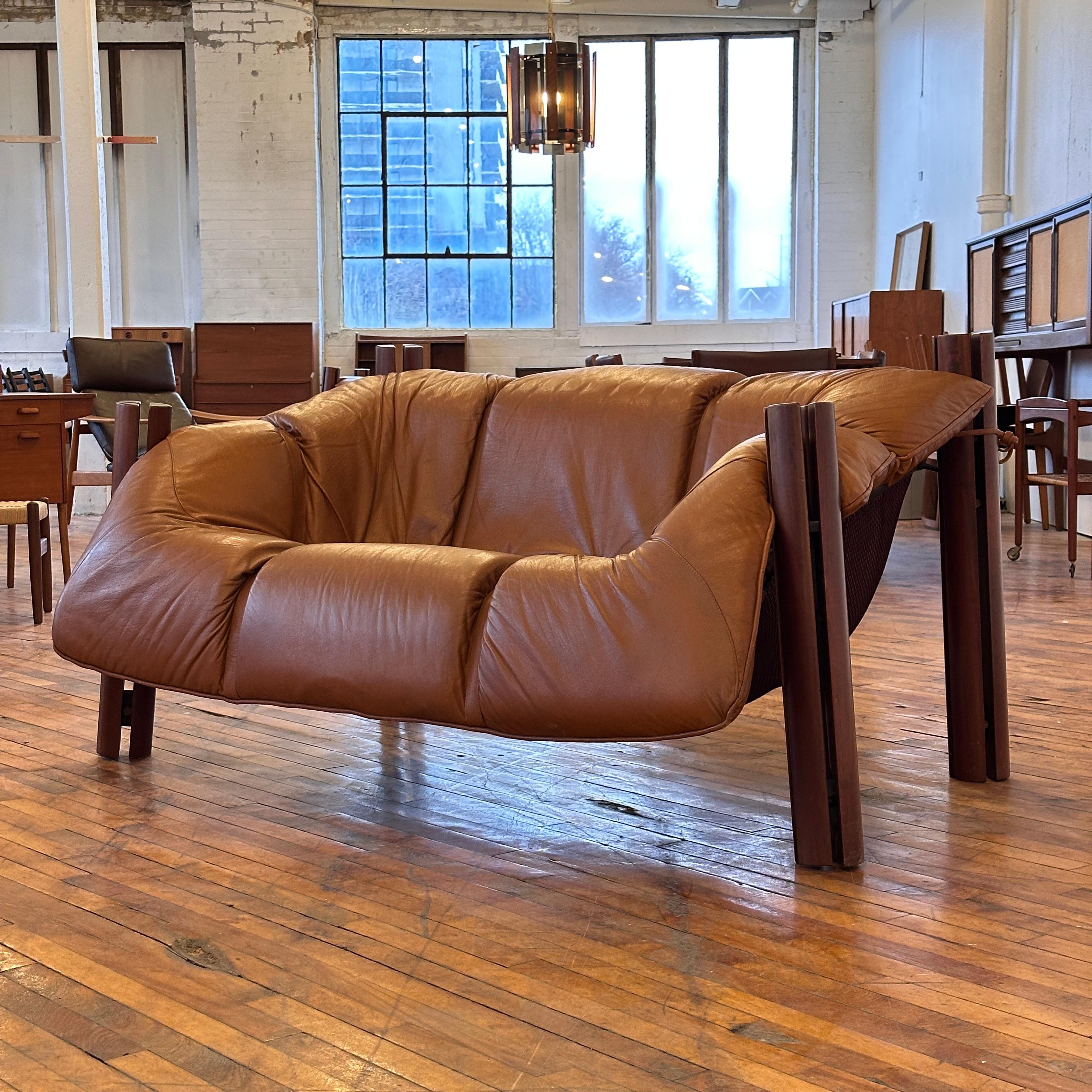 This Percival Lafer MP-211 Loveseat represents the pinnacle of Brazilian modernist design, where organic warmth meets disciplined craftsmanship. Upholstered in sumptuous cognac-colored leather—professionally restored to enhance its natural