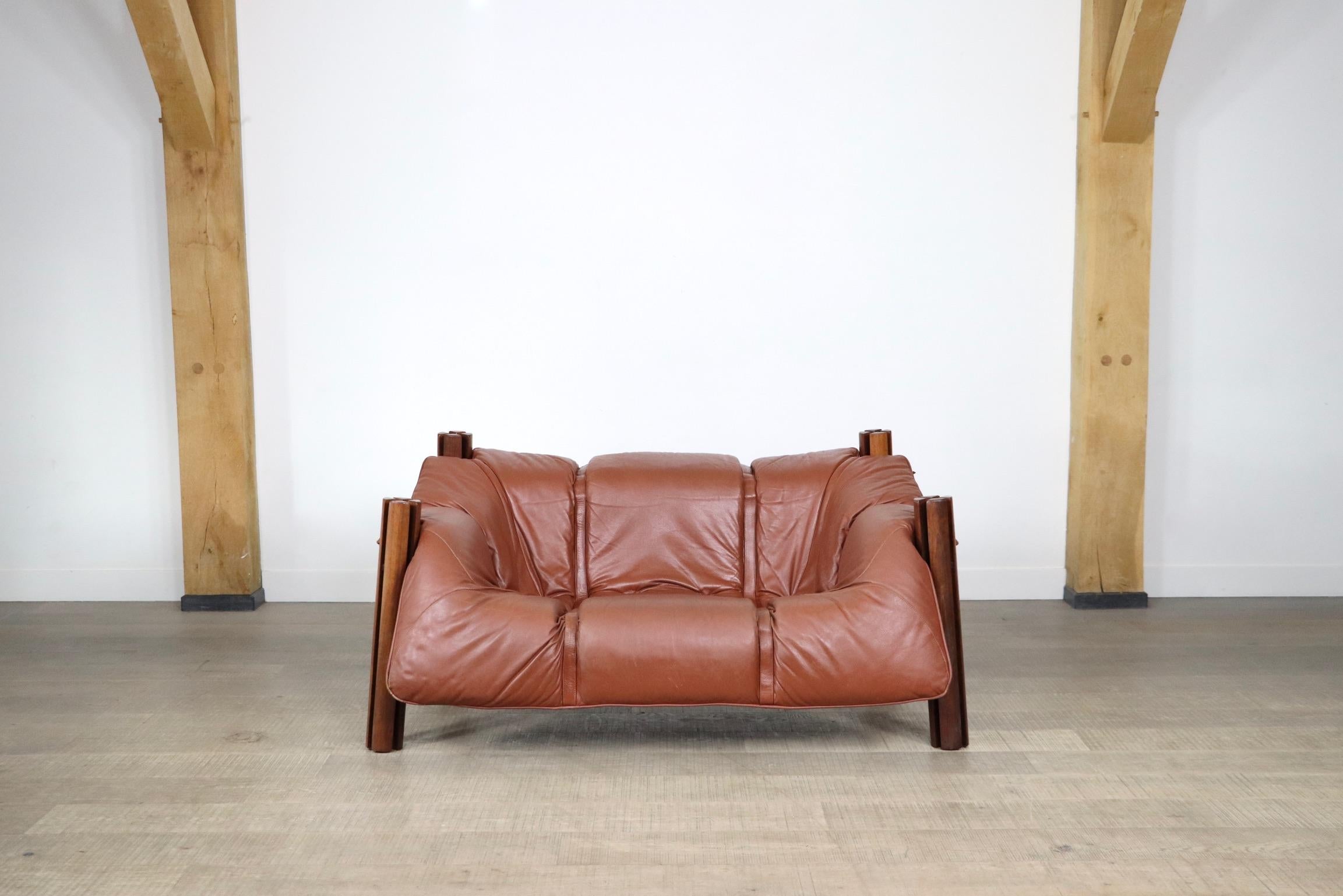 Incredible cognac leather two seater sofa by Percival Lafer. 
The sofa is made of four gorgeous Brazilian hardwood legs which are attached to the metal frame by screws. The cognac leather seating cushion lays in the metal base frame supported by a