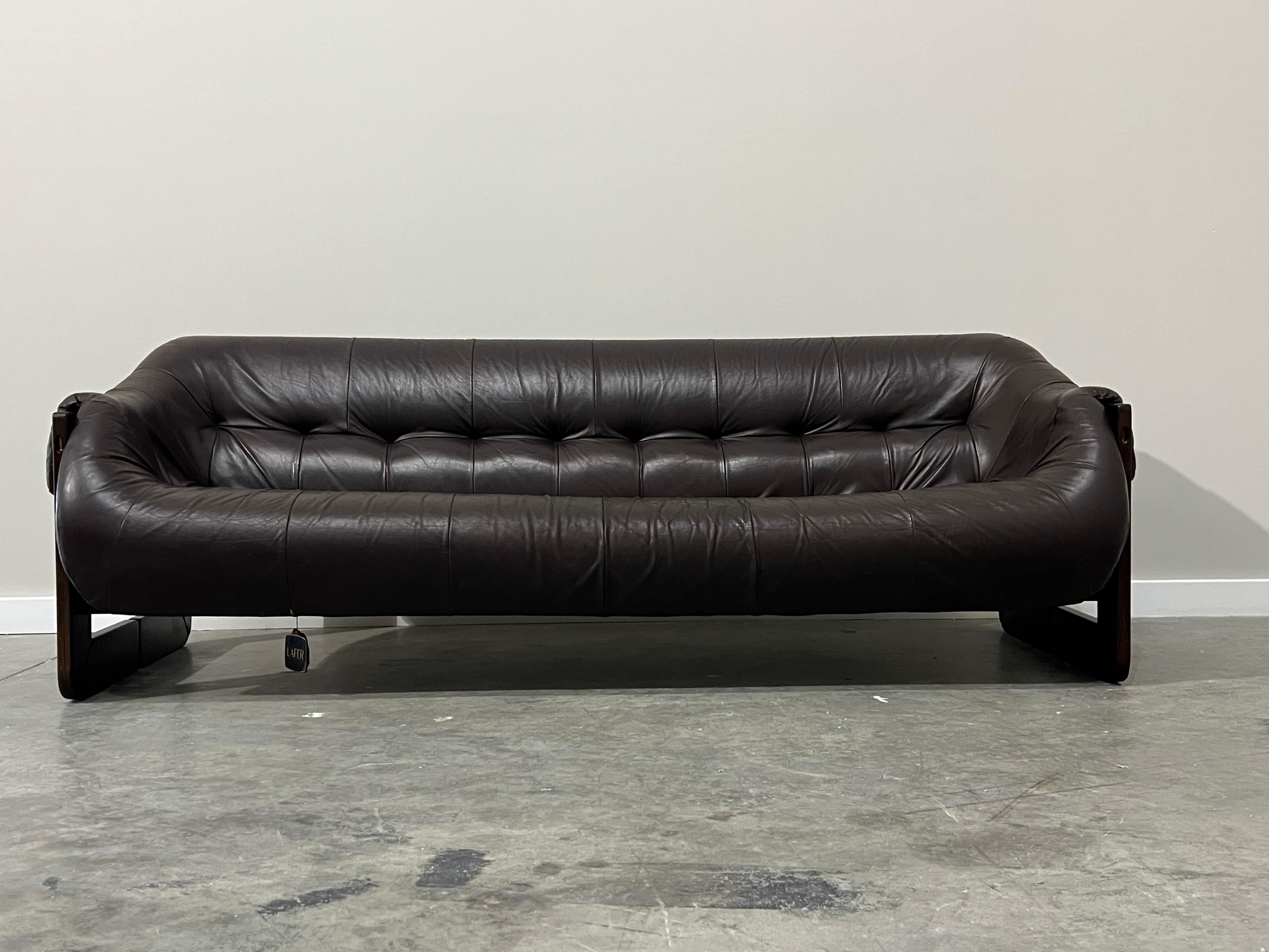 Comfortable and sleek sofa designed by Percival Lafer of Brazil, circa 1970s. Dark chocolate brown leather cushion sits atop leather support straps. The base of the sofa and legs are carved rosewood and the legs are uniquely square shaped. In