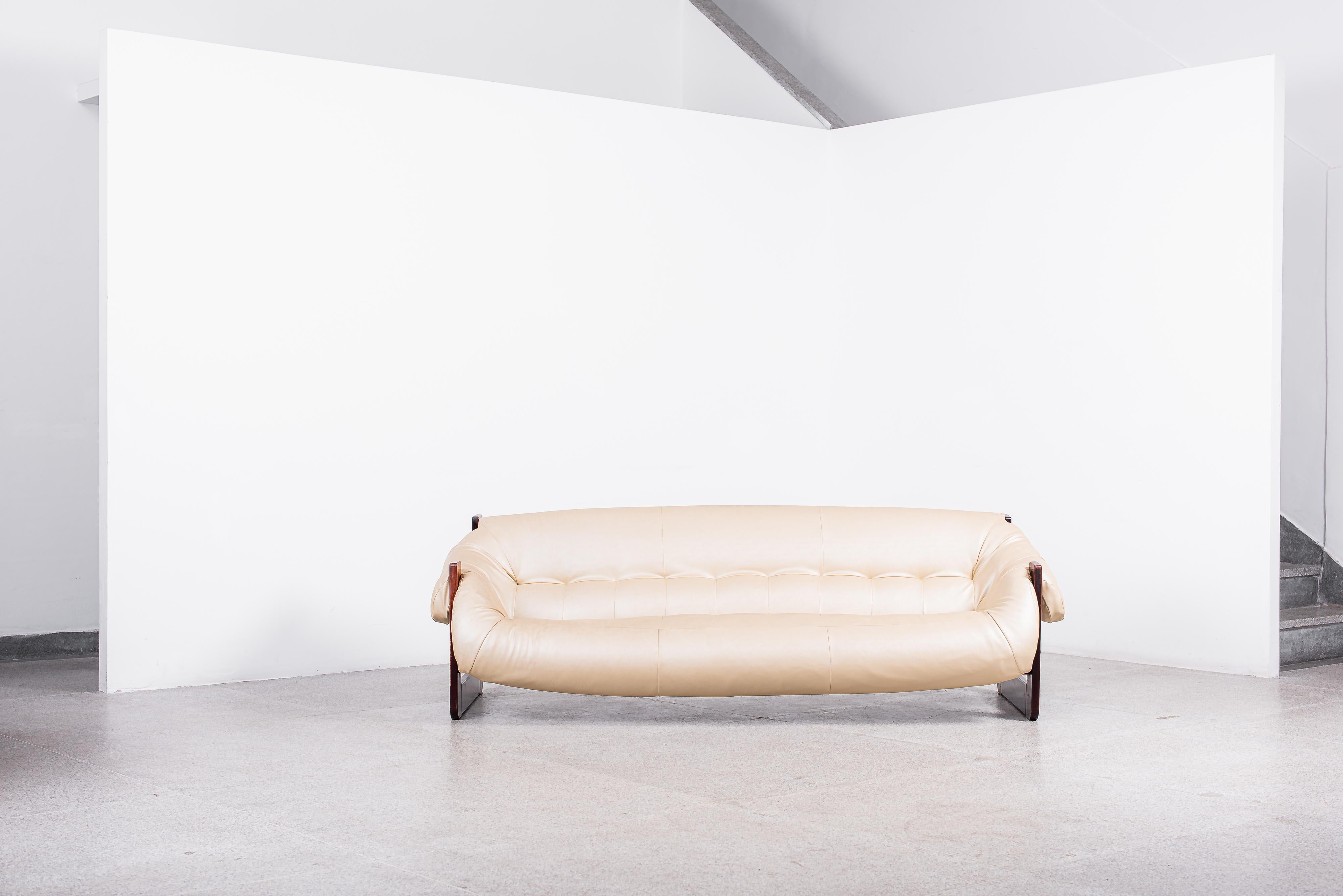 Cómodo y elegante sofá diseñado por Percival Lafer, hacia la década de 1970. El cojín de cuero beige se asienta sobre correas de soporte de cuero. La base del sofá y las patas son de palisandro tallado y las patas tienen una forma cuadrada única. En