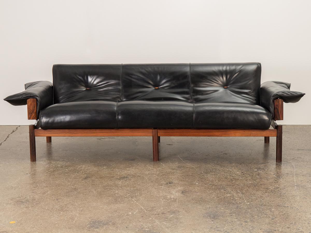 Early and seldom seen MP-013 leather and rosewood sofa with ottoman, designed by Percival Lafer. Stunning Brazilian rosewood structure supports the seat in a unique way so that it appears to float. Nice original black leather is supple and we took