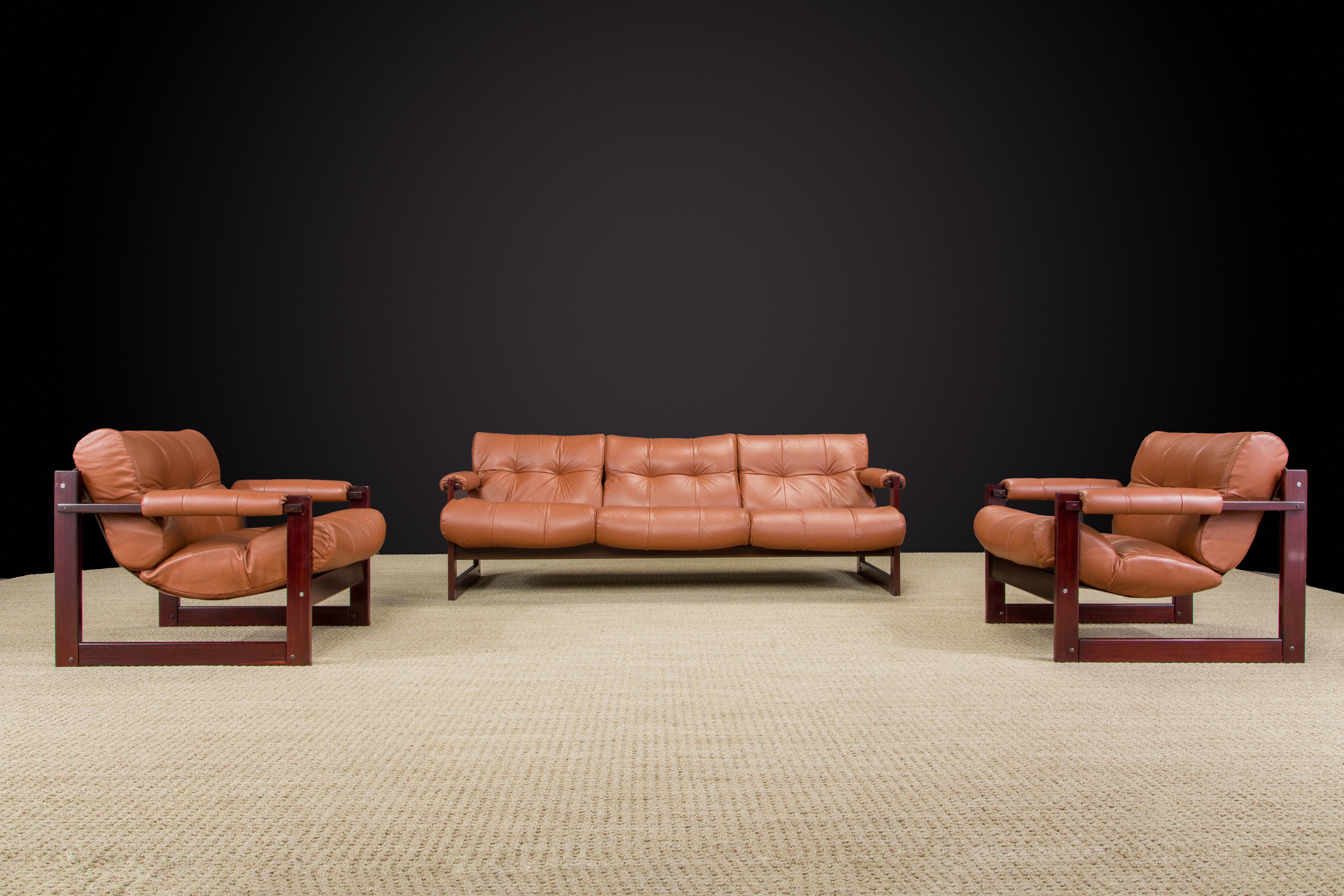 This gorgeous restored 'S-1' living room set comprised of a pair of cognac leather lounge chairs and a three-seat sofa by Brazilian designer Percival Lafer for Lafer MP.  This set was designed in 1976 and was Lafer's concept of merging Brazilian