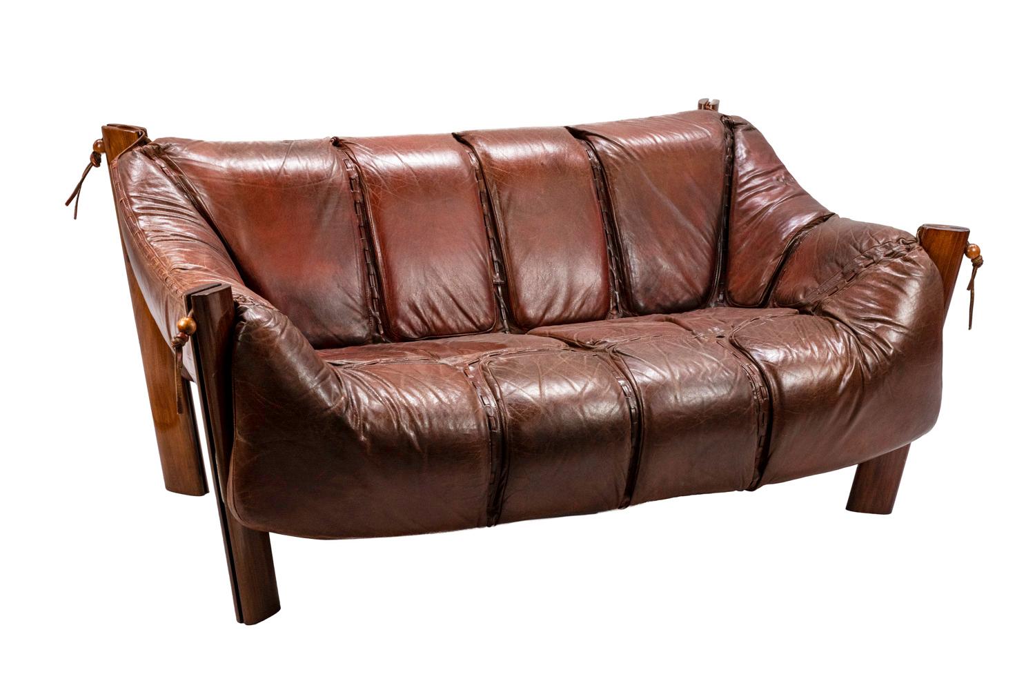 Percival Lafer, attributed to.
Two-seat sofa MP-211 in slightly orange brown leather standing on four rectangular legs with curved angles in Rio rosewood. One-piece seat and back composed by leather parts linked with each others by lattices, hung