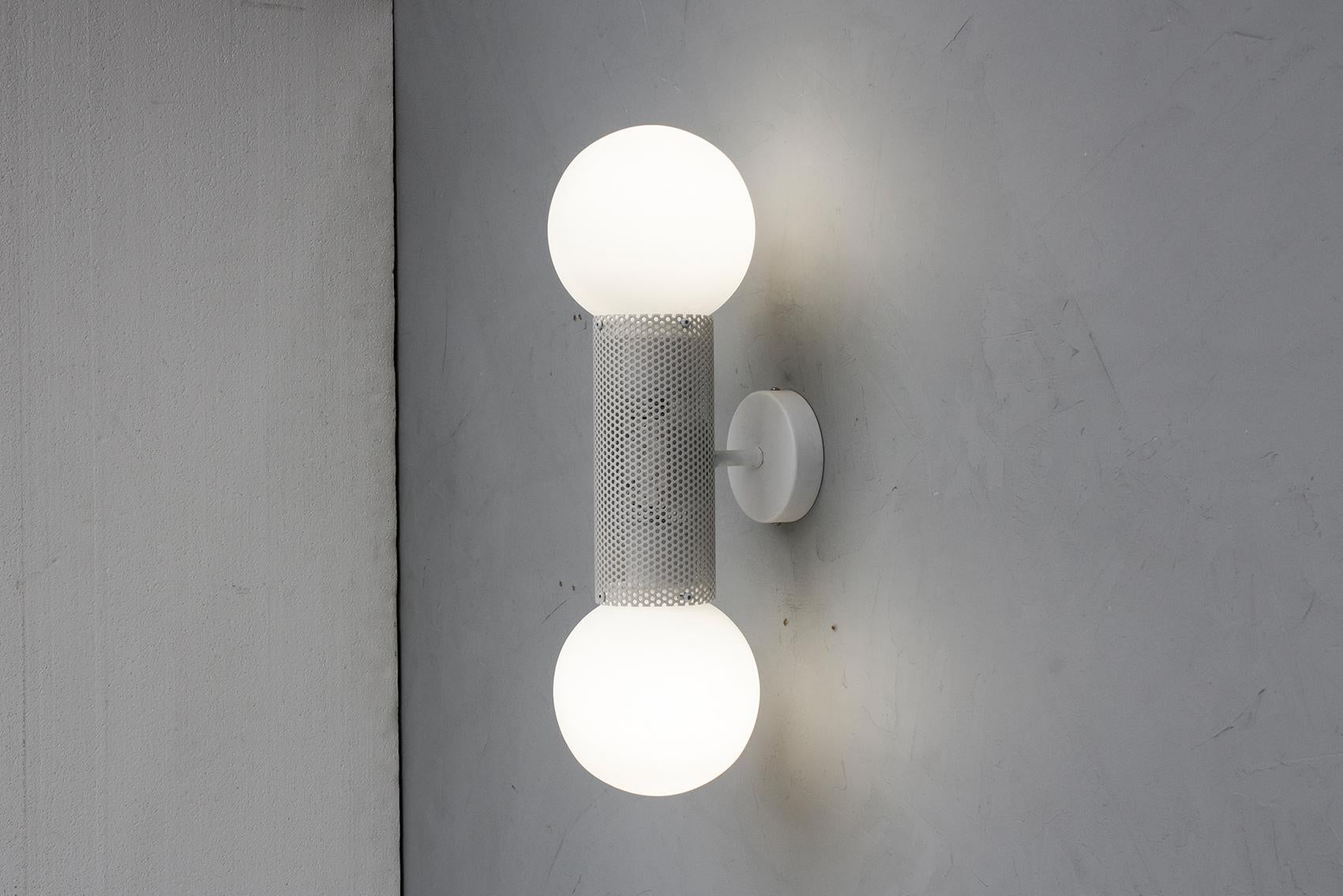 Double the fun with the perf double sconce. Combining hand blown opal glass with a perforated metal housing, perf sconce is an elemental and versatile decorative fixture.
Utilising two low energy LED bulbs, perf double sconce is available in 3