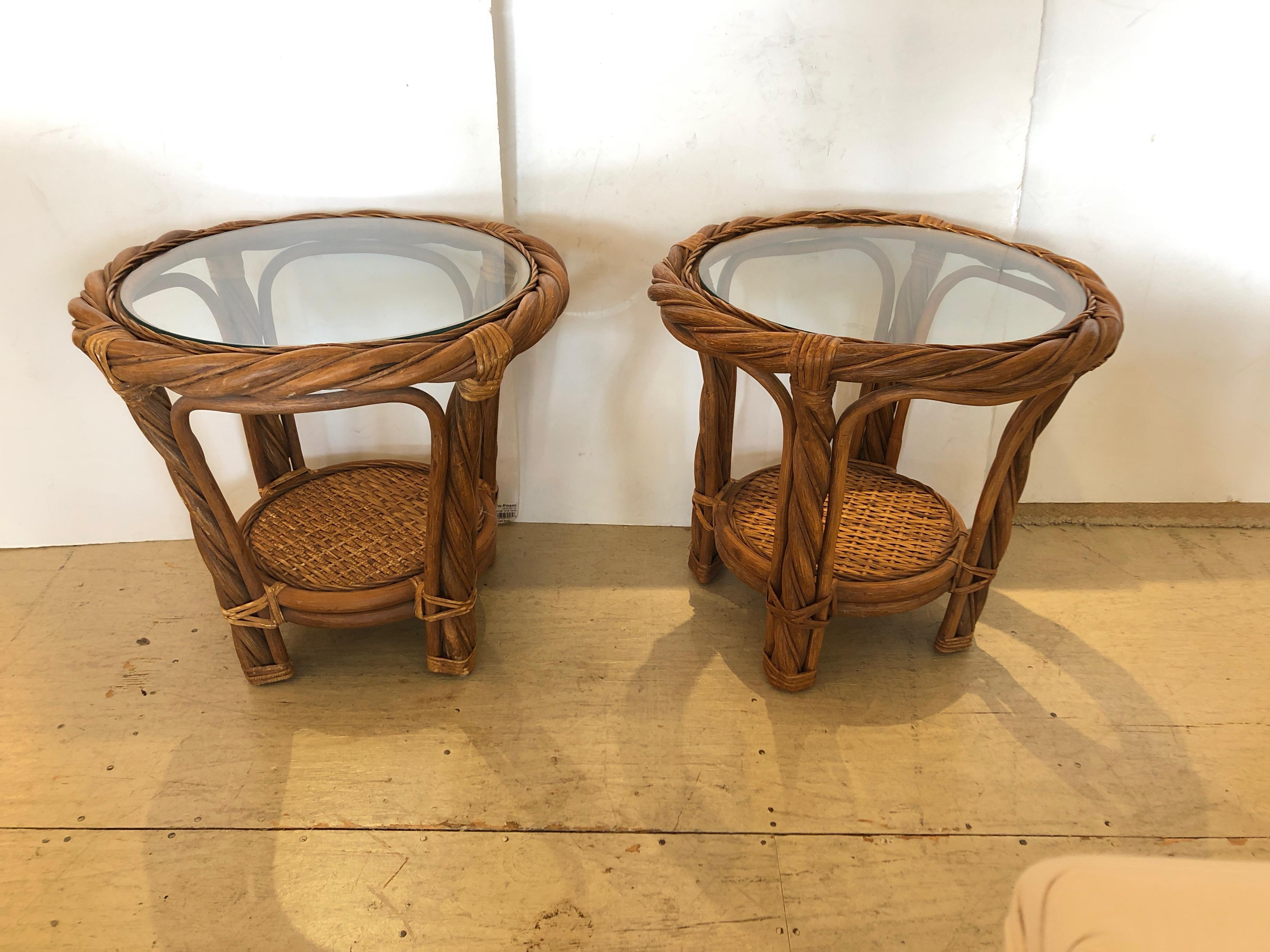 Two handsome round side or end tables made of rattan, bamboo and wicker, having two tiers and inset glass tops. Solid sturdy construction and very classy.