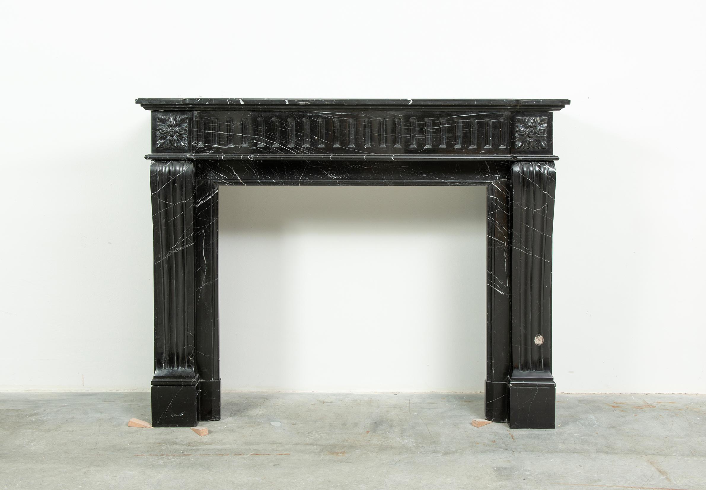 Petite Louis XVI Fireplace Mantel in black marble with striking white veins.

This little French mantel has a nice crisp profiled topshelf above a fluted frieze with lovely decorative floral endblocks that rest on shaped jambs above a sturdy plain