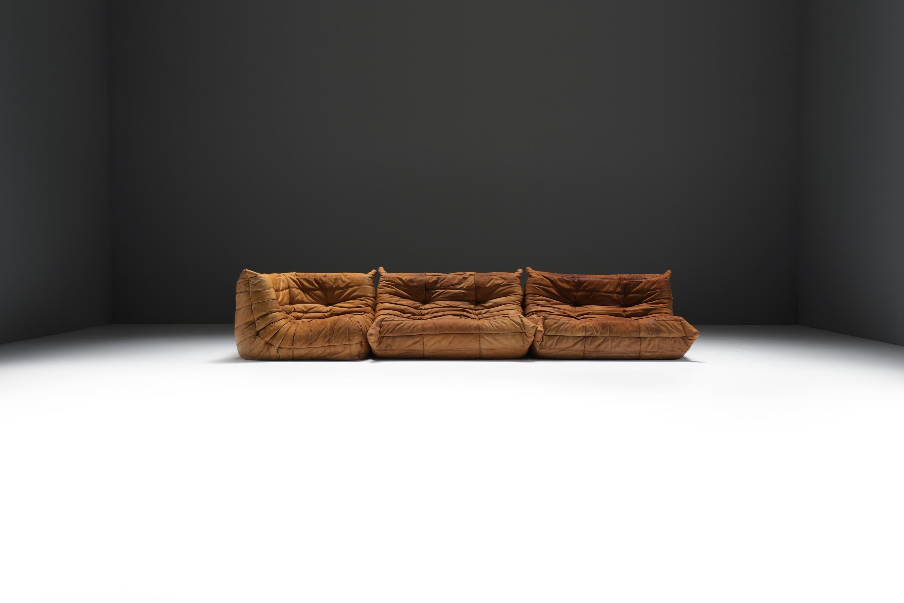 This Togo sofa set features an exquisite and exceptionally rare natural patinated cognac leather upholstery, making it a standout addition to any interior. 
With its superior craftsmanship and timeless vintage design, this piece exudes elegance and
