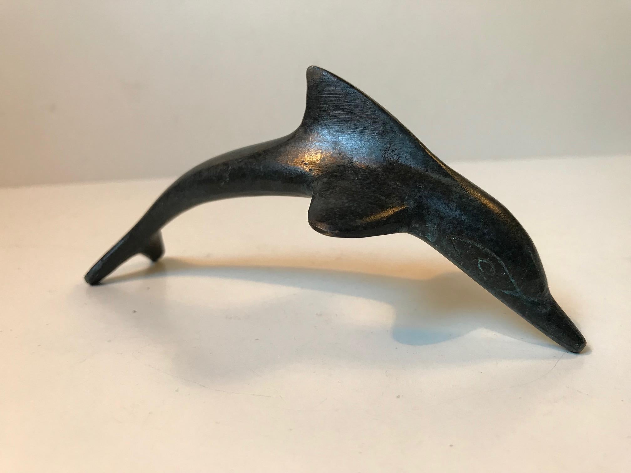 A patinated desk sculpture in shape of a small dolphin. The precise provenance is unknown. But is was made in Europe during the 1920s or even a bit prior. It is signed/marked indistinguishable to its fin.
