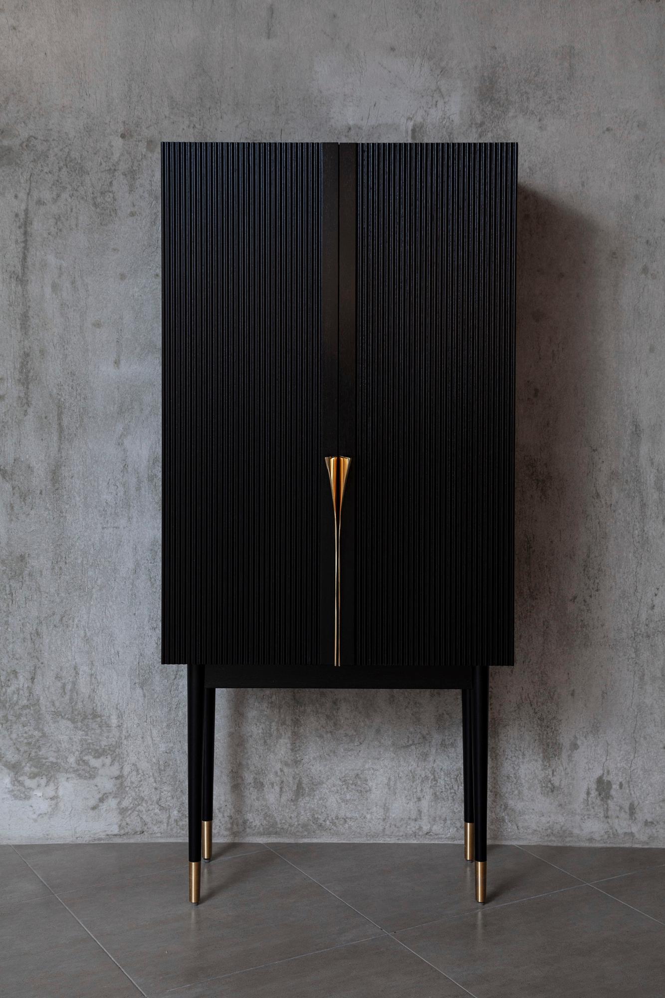 Bar cabinet made of solid seike wood body with Ébano finish, details in lathed bronze, interior surfaces laminated with stainless steel sheets, interior back panel with antique mirror glass, and bronze sand-casted handles. 

The first Perfidia