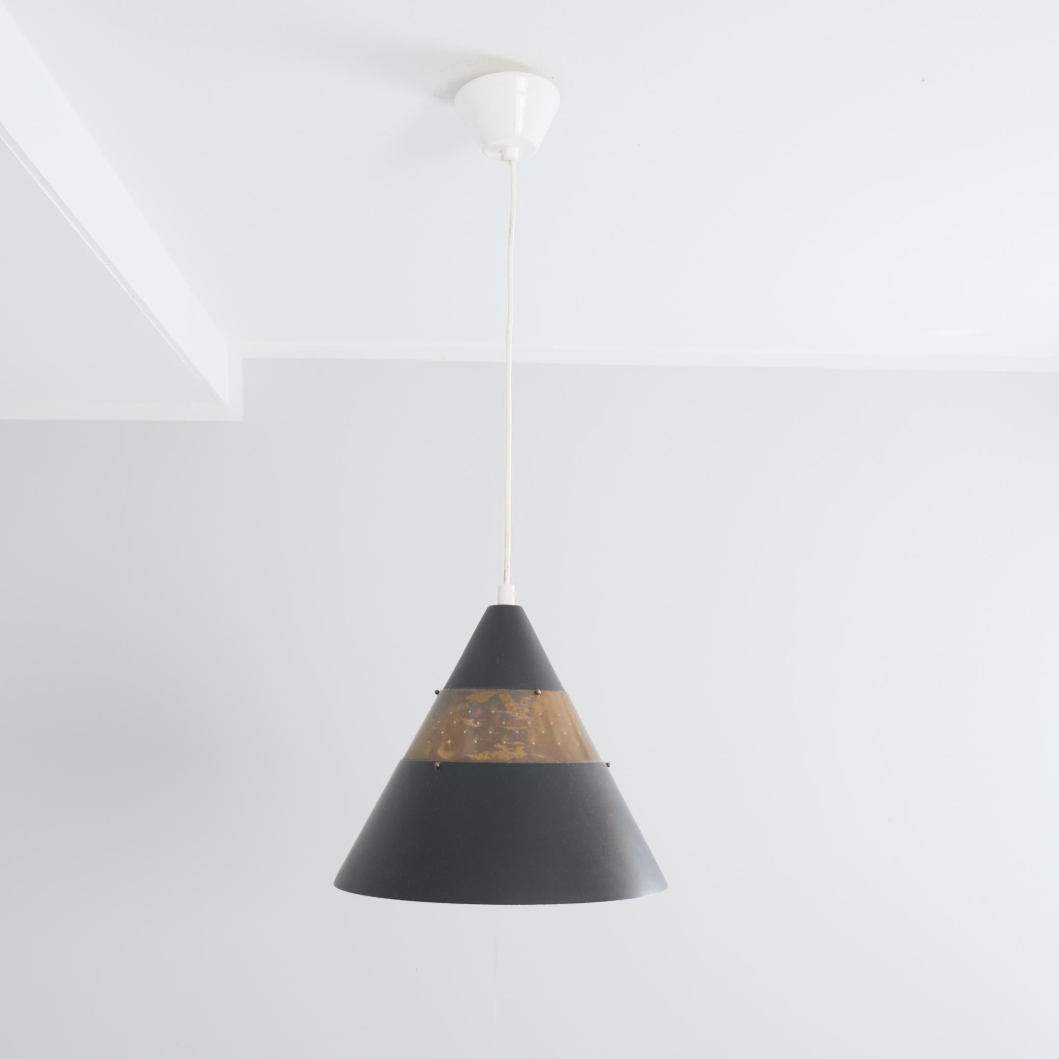 Suspension de plafond en forme de cône, perforée et stratifiée, réalisée par Maria Lindeman pour Idman. La lampe est composée de trois couches de métal, deux en gris foncé et une en laiton perforé. La lampe est dans son état d'origine et présente