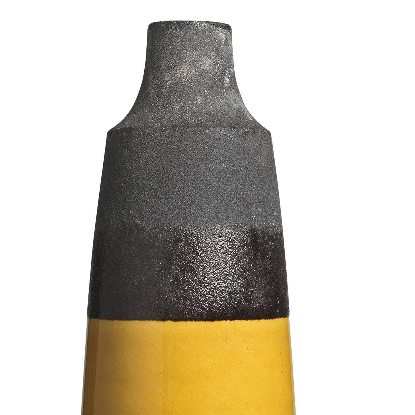 This unique vase features a tall cylinder-like shape and a slender mouth, perfect as a centerpiece holding a single flower. The color block pattern glazing the surface of the vase is in black lava on top and bright yellow on the bottom, which has a