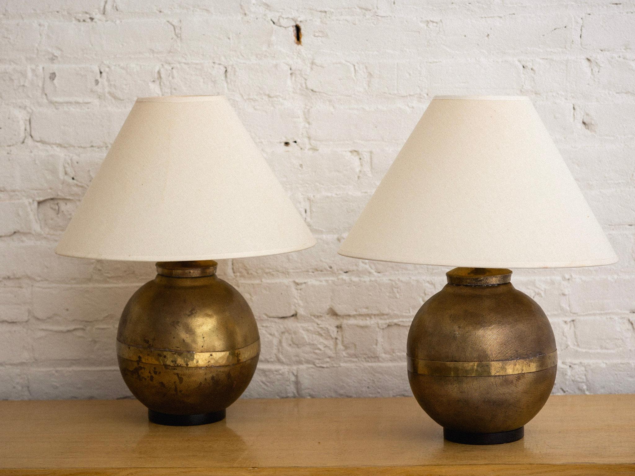 A pair of perforated brass globe lamps on painted wood bases. Heavy patina has developed with age. Harps included. Lamp shades not included. Harps add an additional 6 inches to listed height.